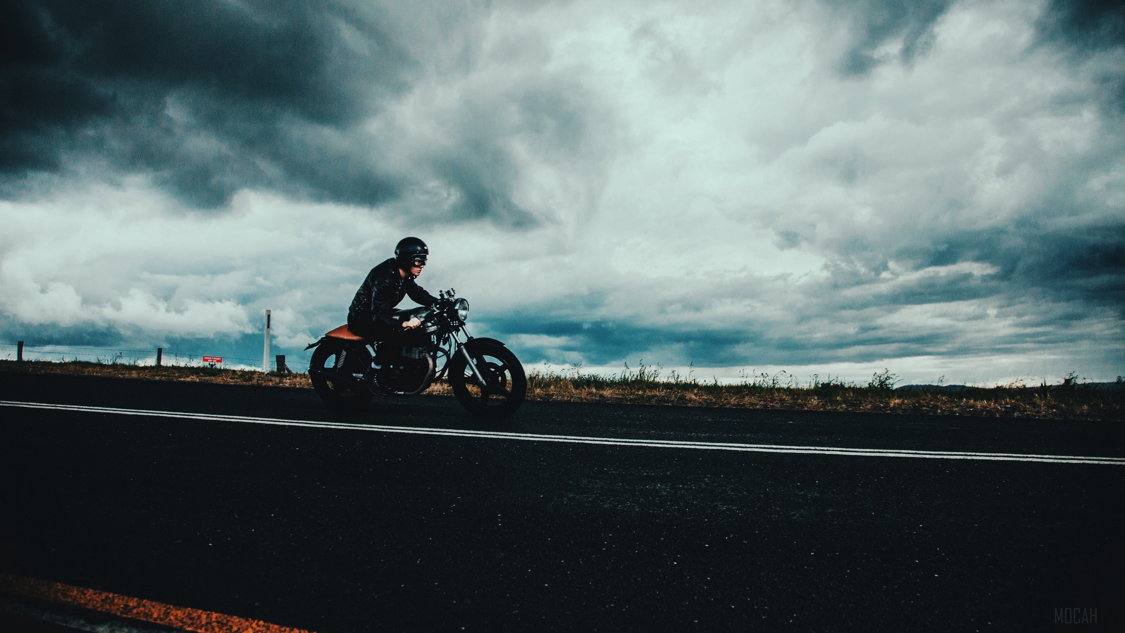 Motorcyclist on a road under overcast sky HD Wallpaper