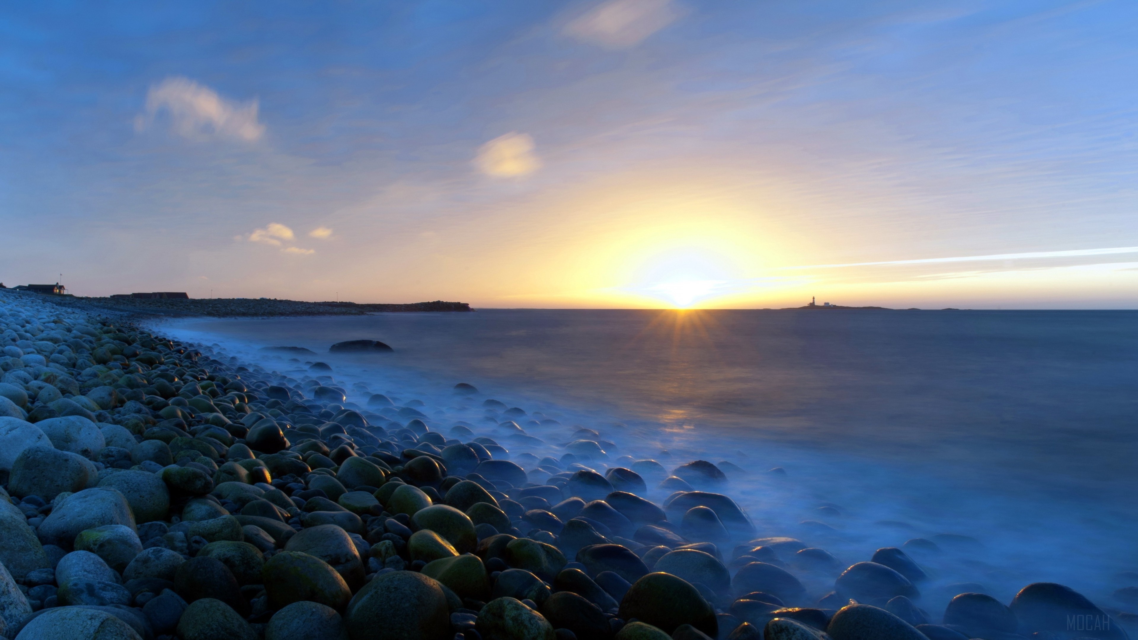 Sunset over a rocky beach with a lighthouse HD Wallpaper