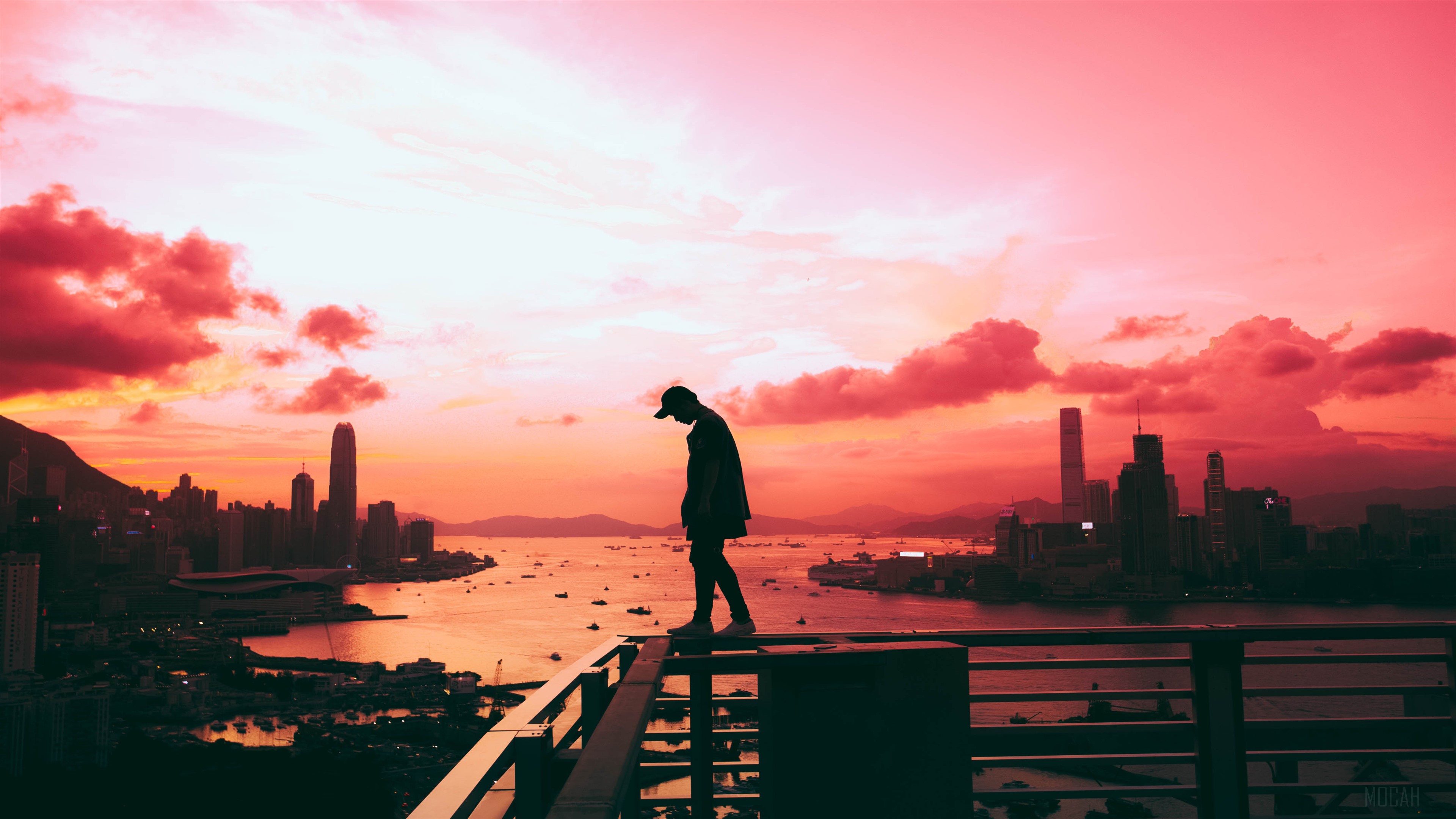 Silhouette of a man on a rooftop overlooking Hong Kong at sunset HD Wallpaper