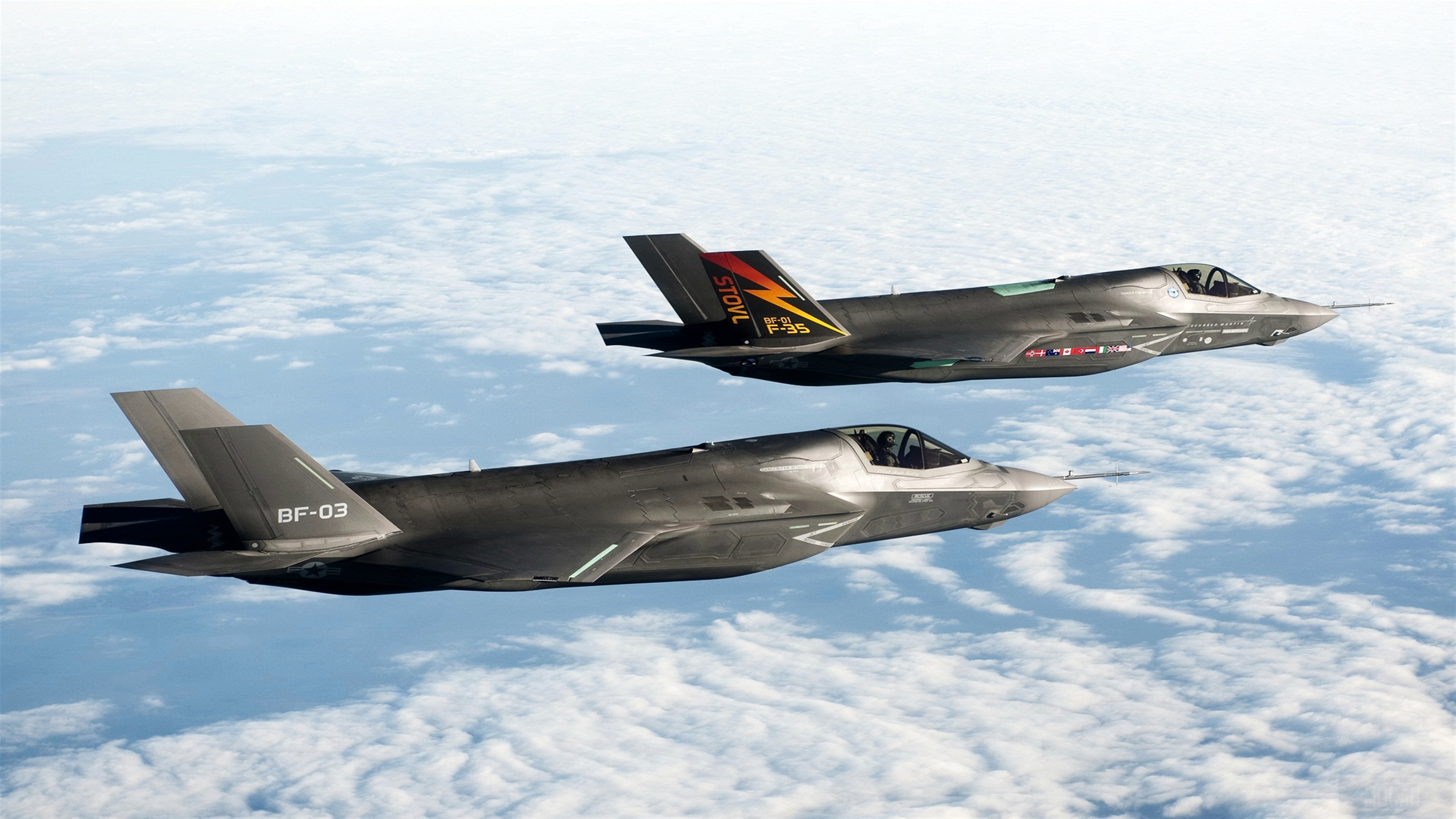 Two F-35 fighter jets flying above clouds HD Wallpaper