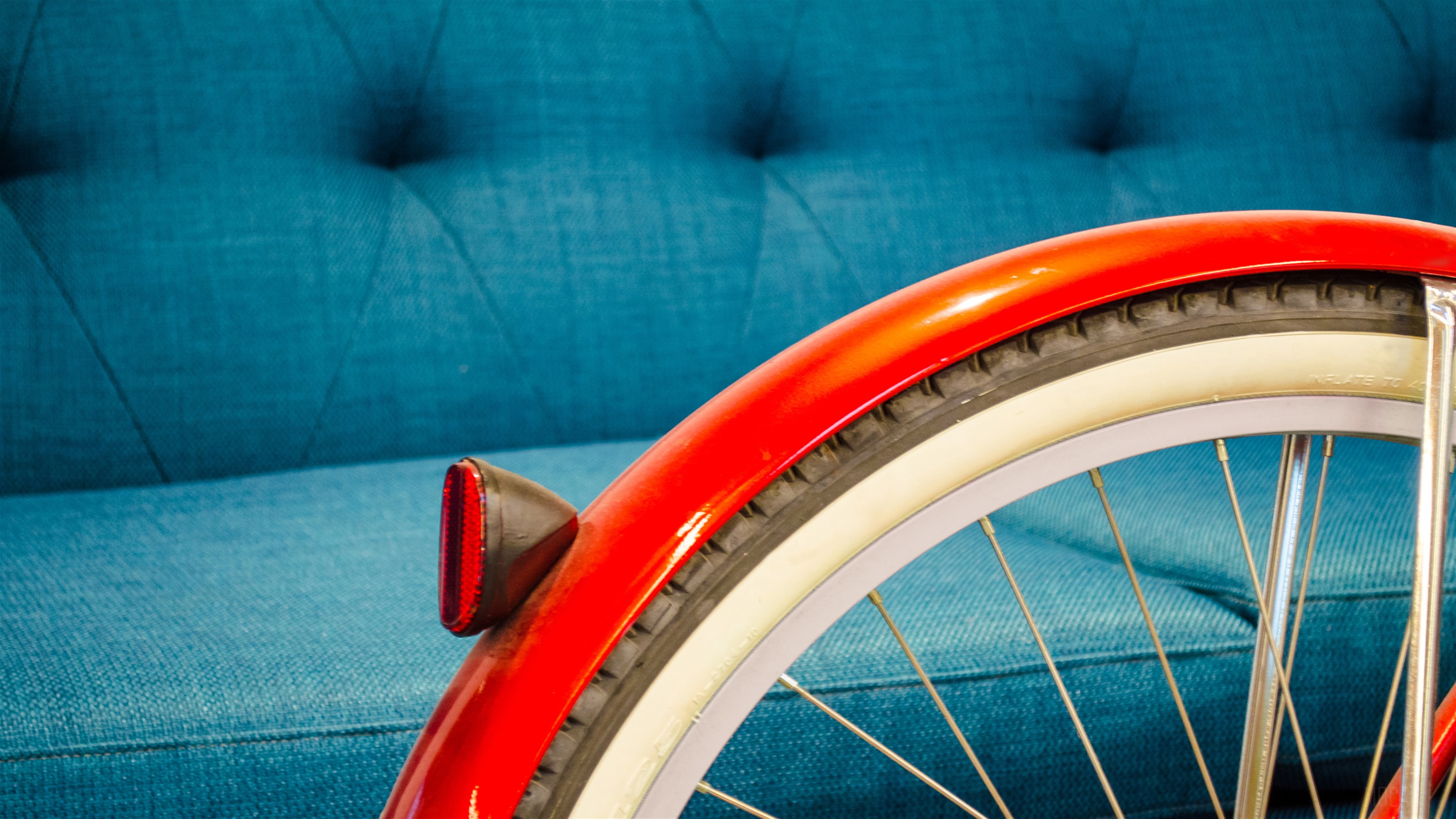 Red bicycle fender and wheel on blue couch HD Wallpaper