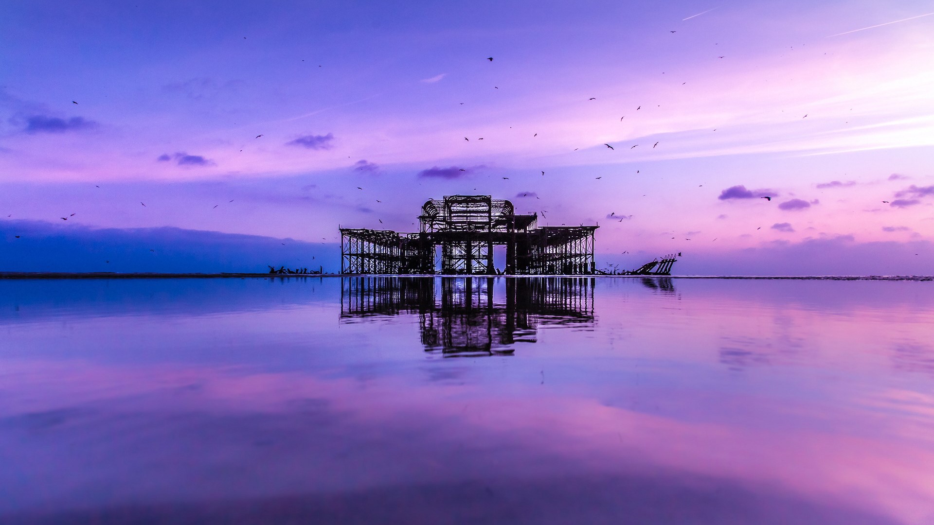 Ruined pier reflected in water at sunset HD Wallpaper
