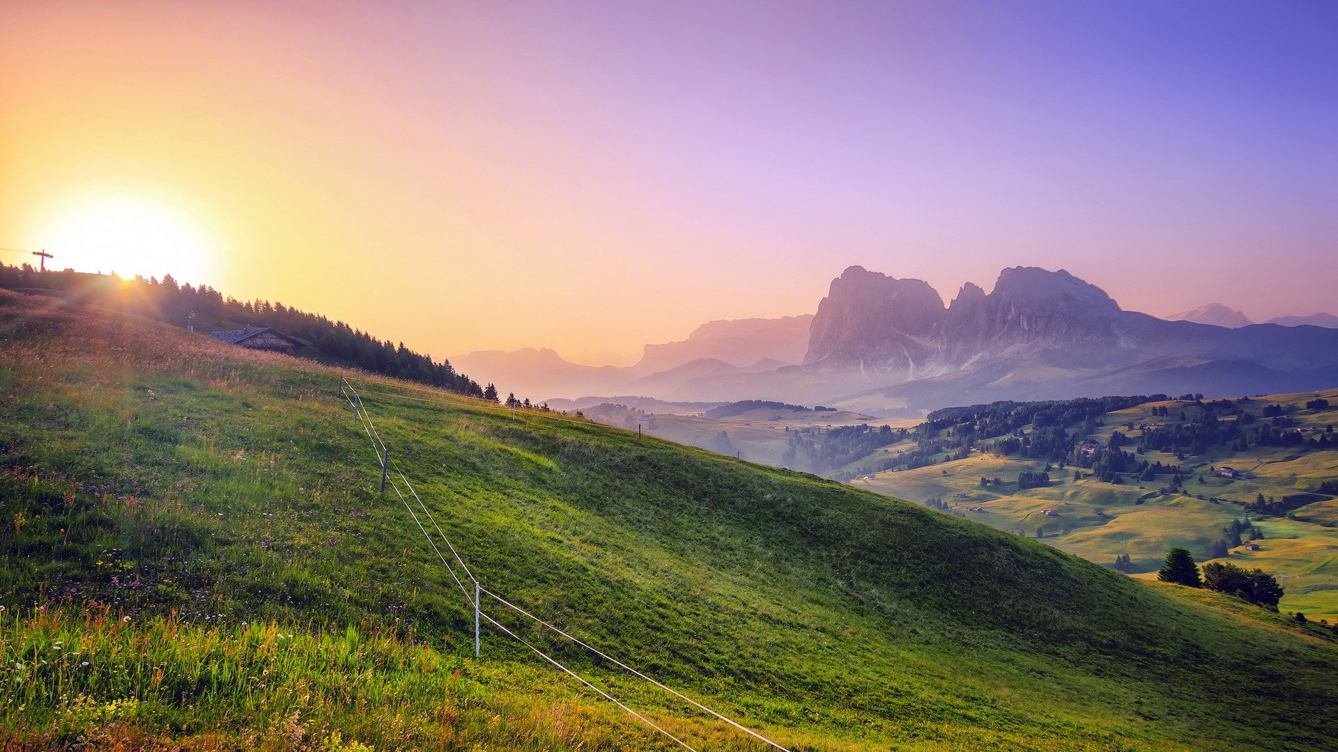 Sunrise over a green mountain landscape with distant peaks HD Wallpaper