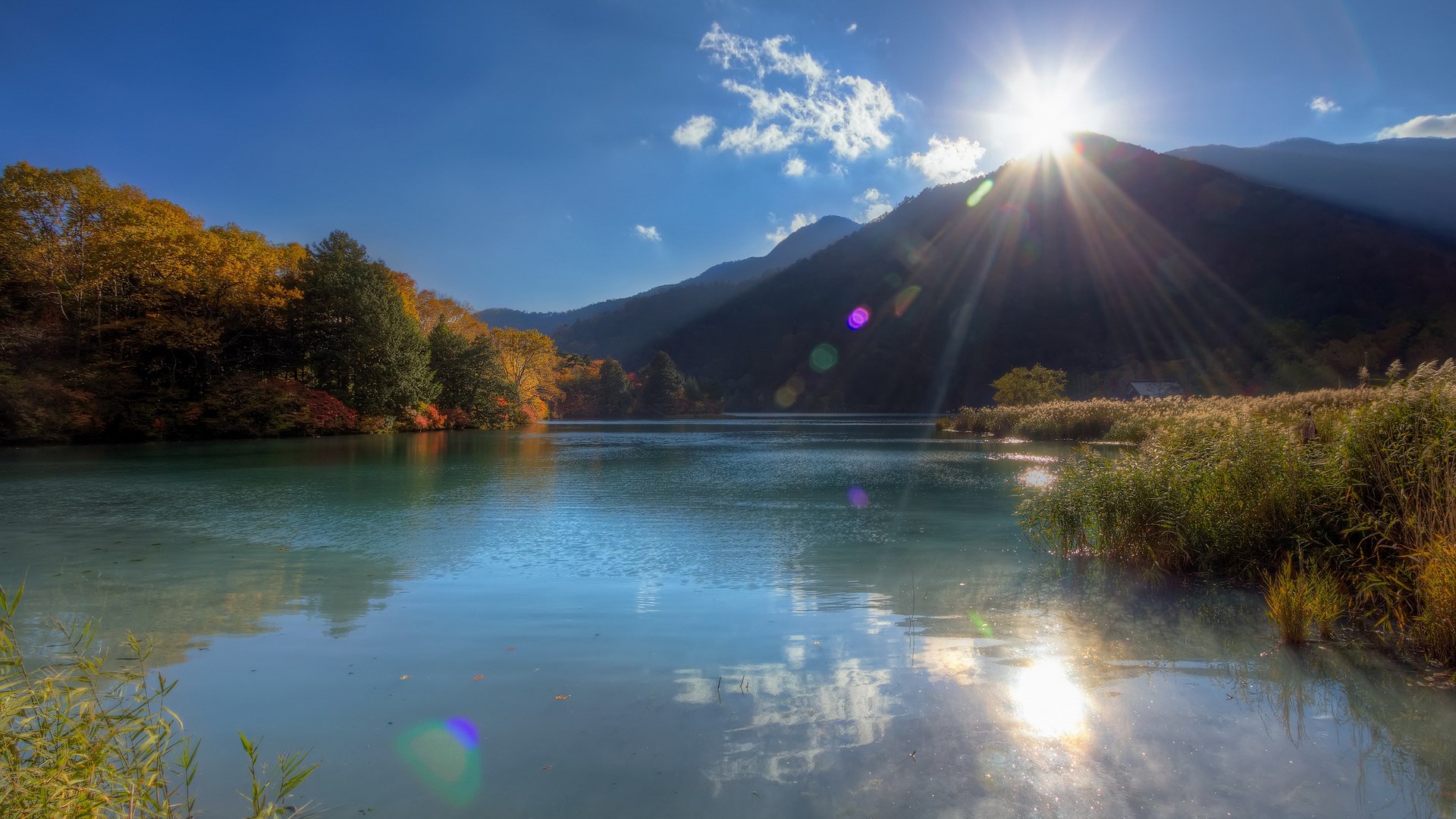 Lake and mountains during autumn with sun flare HD Wallpaper