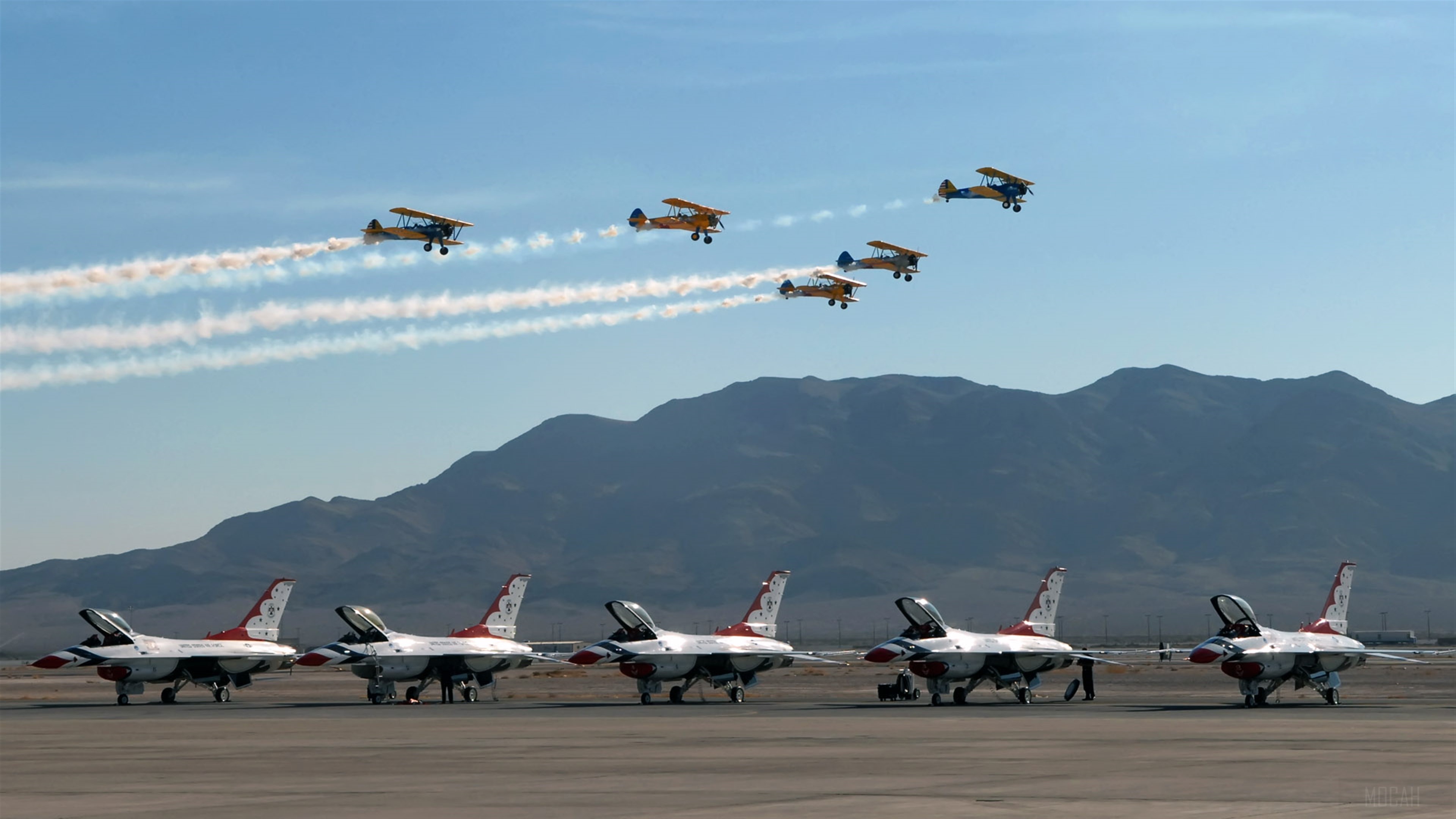 Biplanes perform aerial maneuvers with fighter jets on tarmac HD Wallpaper