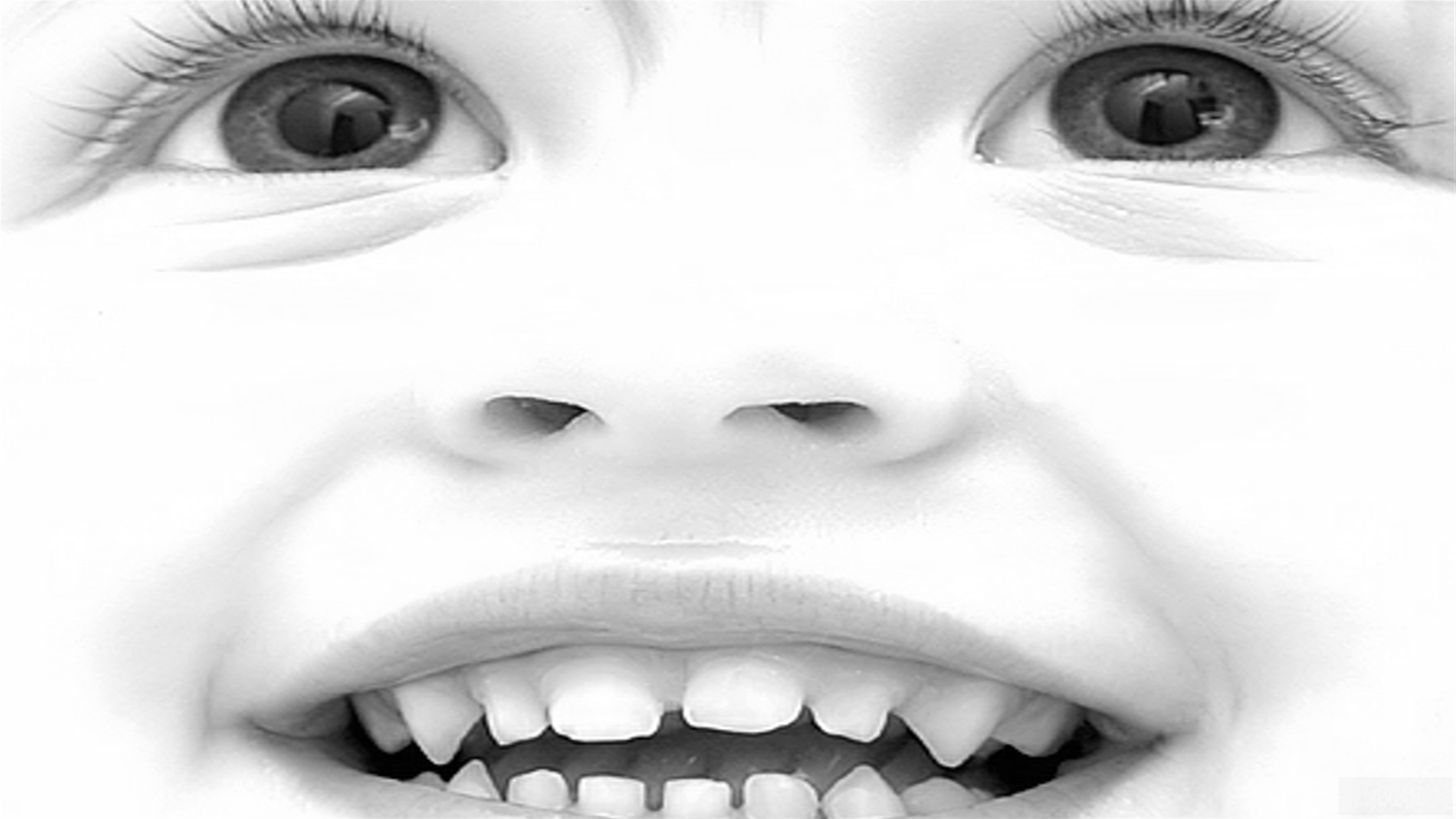 Close-up of a baby's smiling face with eyes and teeth HD Wallpaper