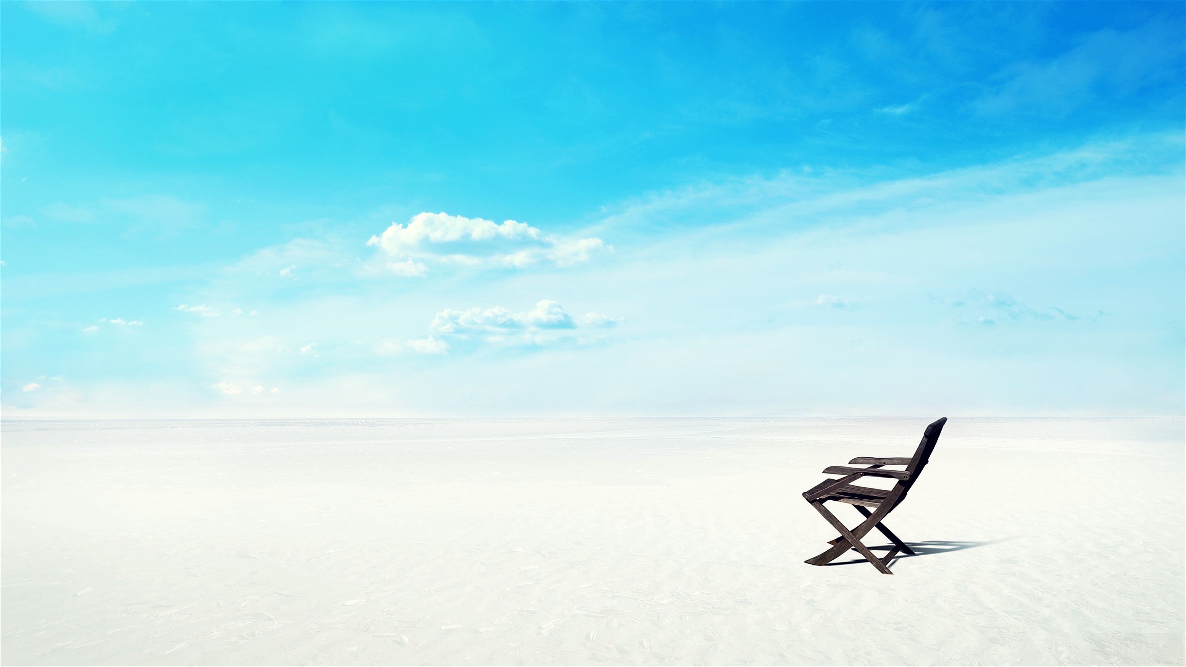 Empty chair on a white beach under a blue sky HD Wallpaper