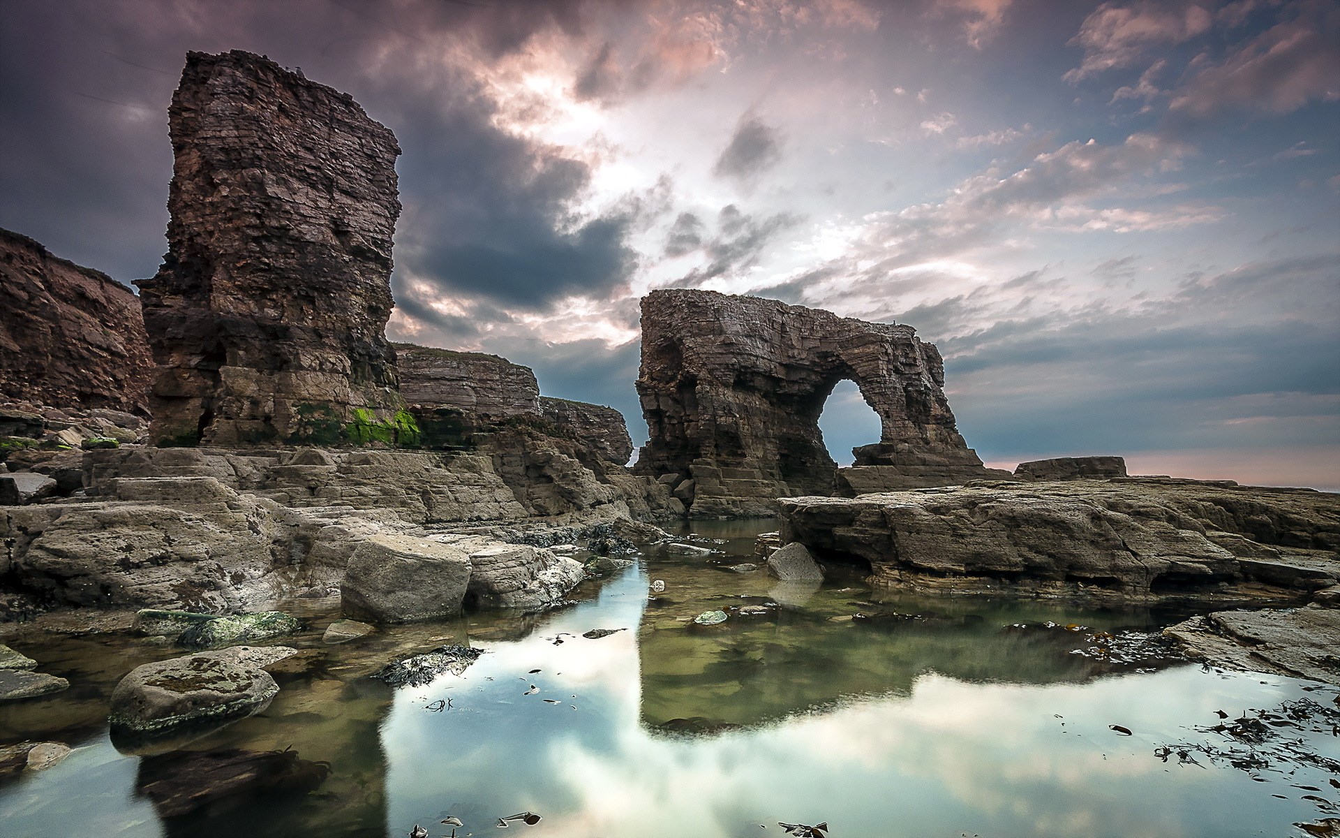 Rocky coastline with sea arch and dramatic sky HD Wallpaper
