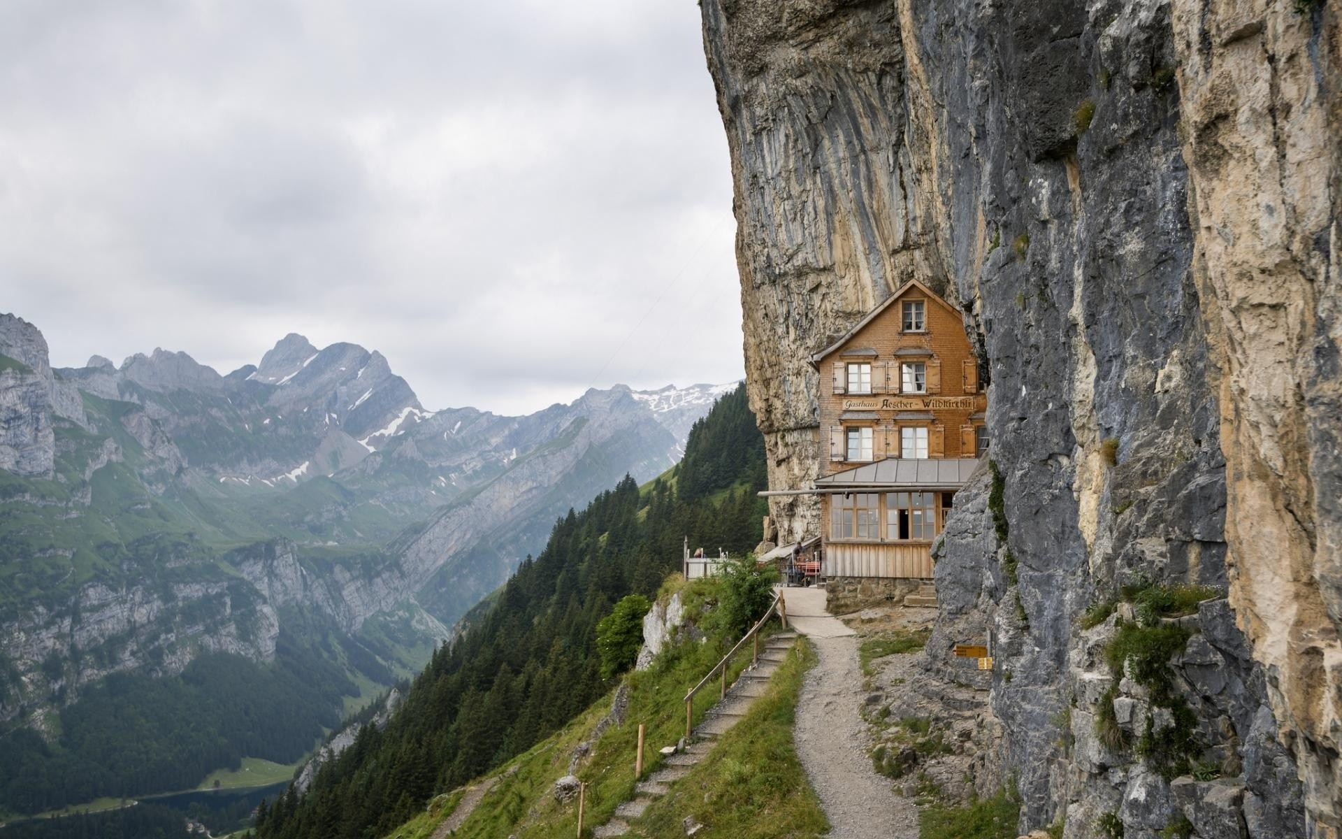 Restaurant built into a cliff face with mountains HD Wallpaper
