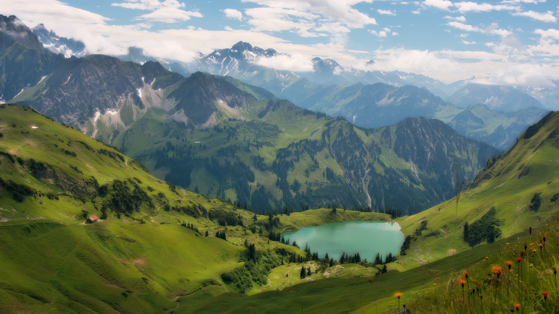 Turquoise mountain lake surrounded by green hills and rocky peaks HD Wallpaper