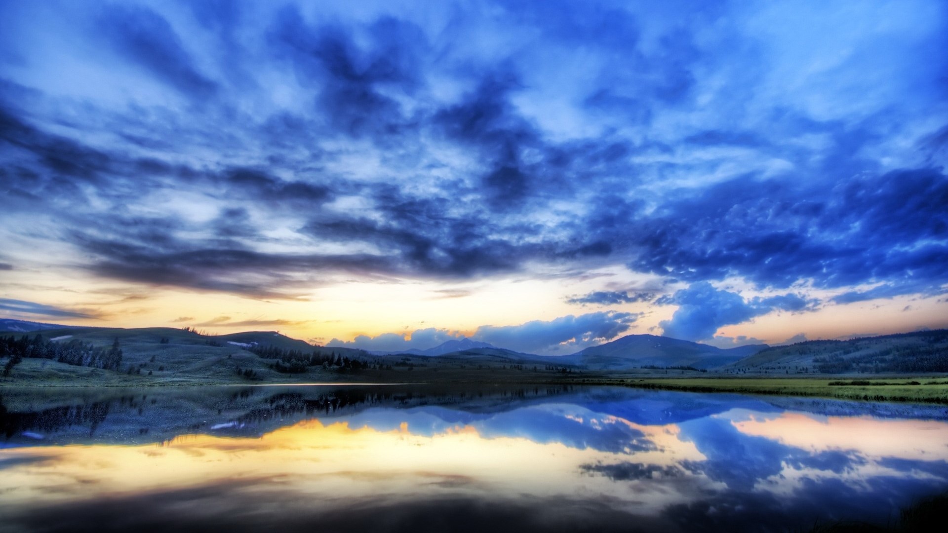 Dramatic sunset over a calm lake with reflections HD Wallpaper