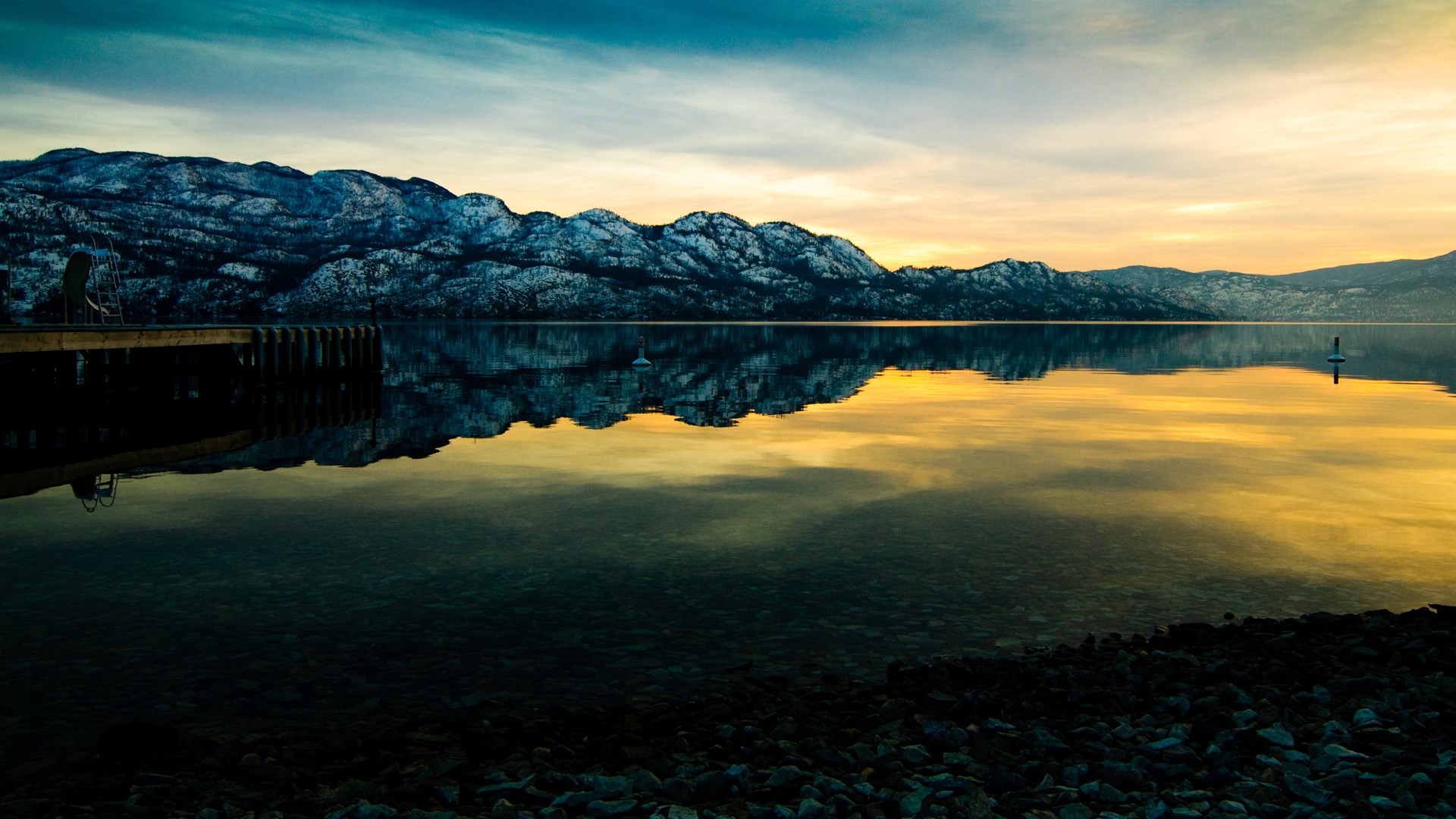 Snow-capped mountains reflected in a calm lake at sunset HD Wallpaper