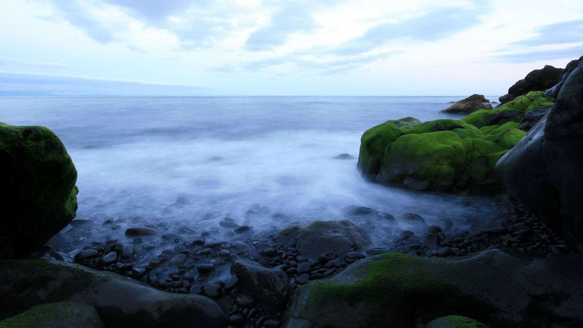 Mossy rocks on a rocky shore with ocean waves HD Wallpaper