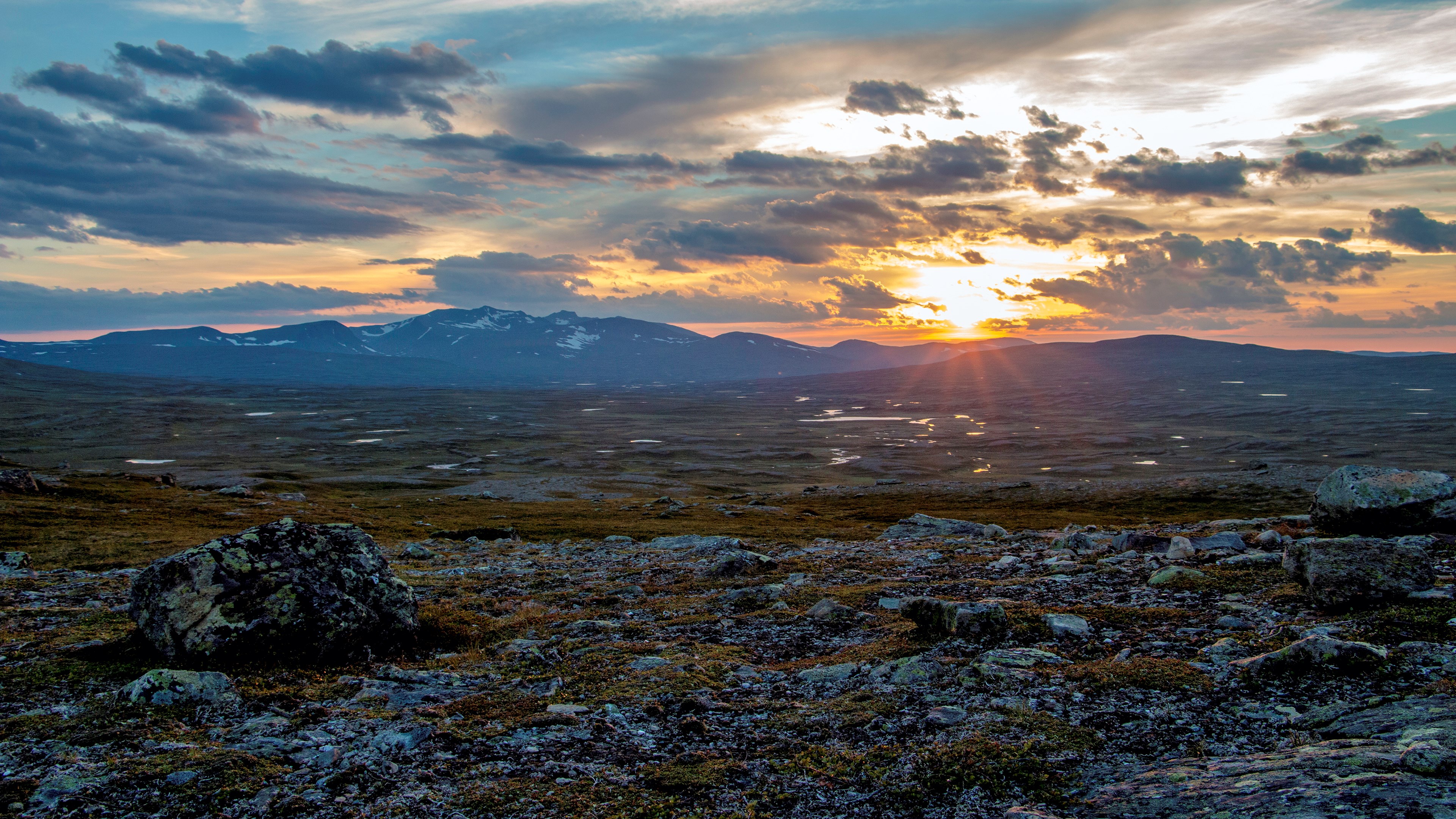 Sunset over a rocky, mountainous landscape with clouds HD Wallpaper