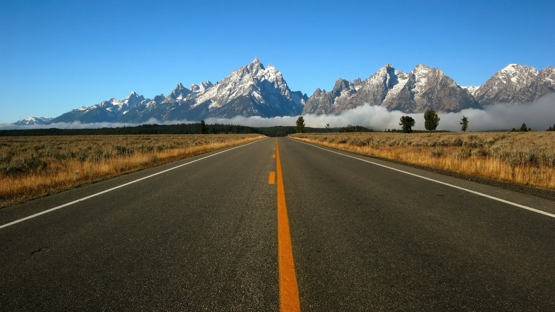 Road leading to snow-capped mountains and clouds HD Wallpaper