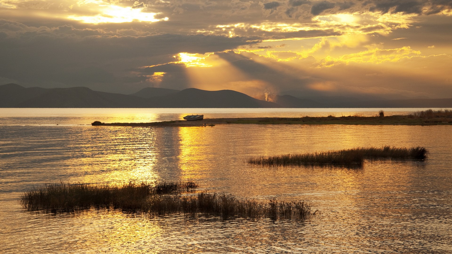Sunset over a calm lake with mountains in the distance HD Wallpaper