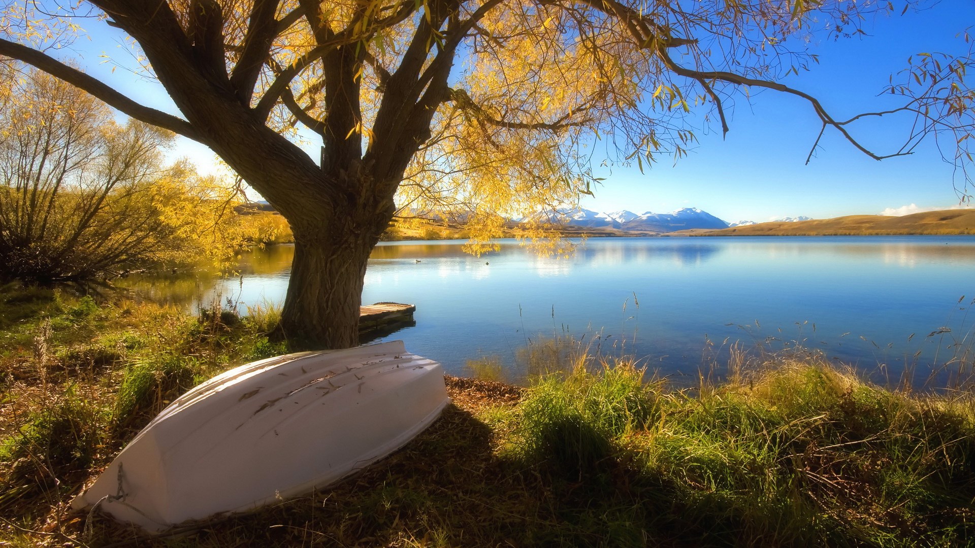 Boat by a lake with autumn trees and mountains HD Wallpaper