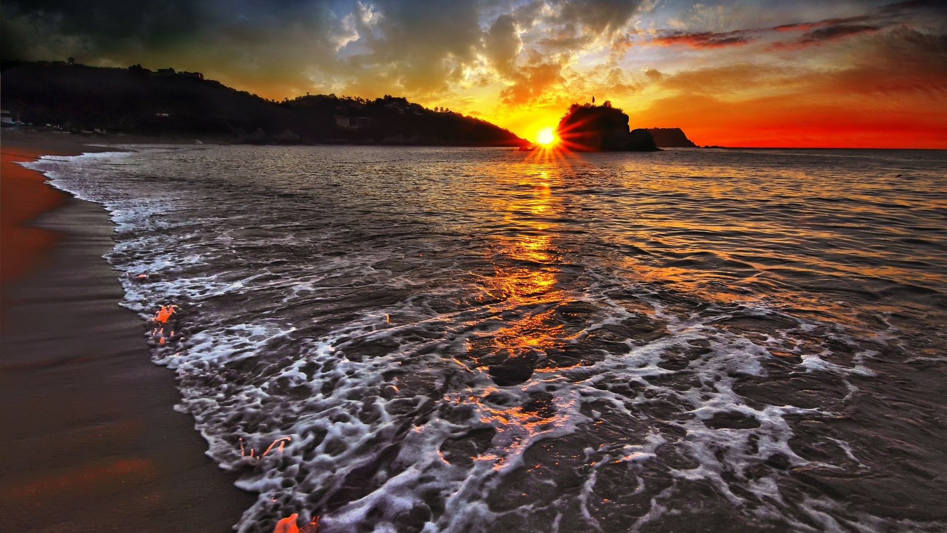 Sunset over the ocean with waves crashing on the beach HD Wallpaper