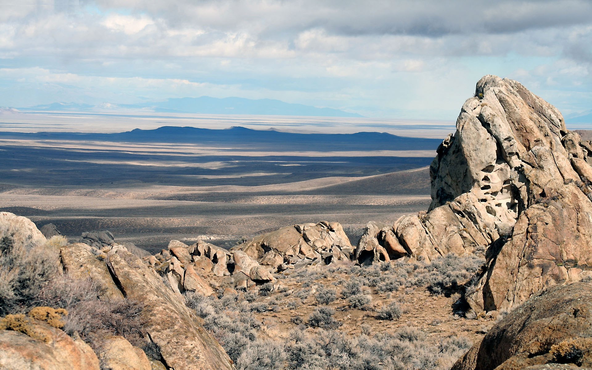 Rocky desert landscape with distant mountains HD Wallpaper