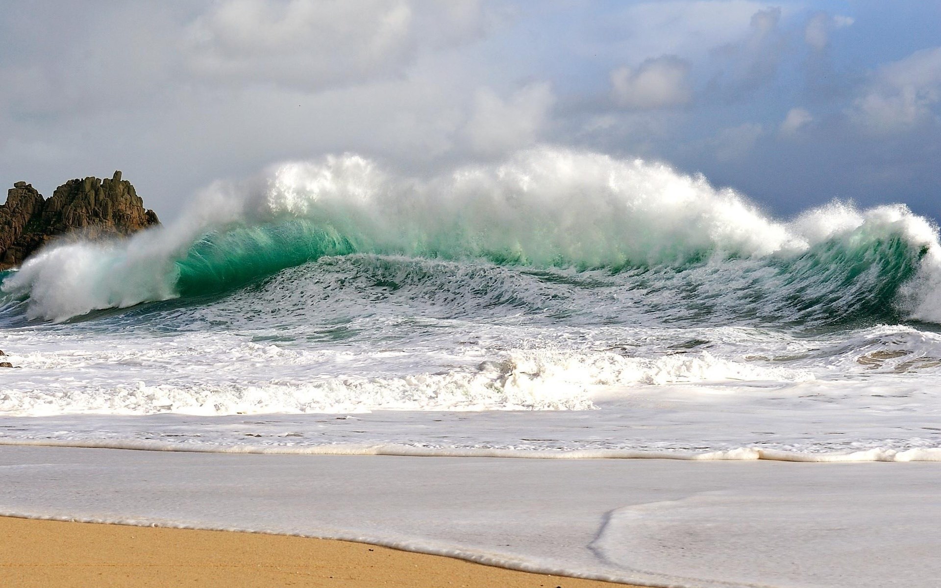 Crashing wave on a sandy beach with rocks HD Wallpaper