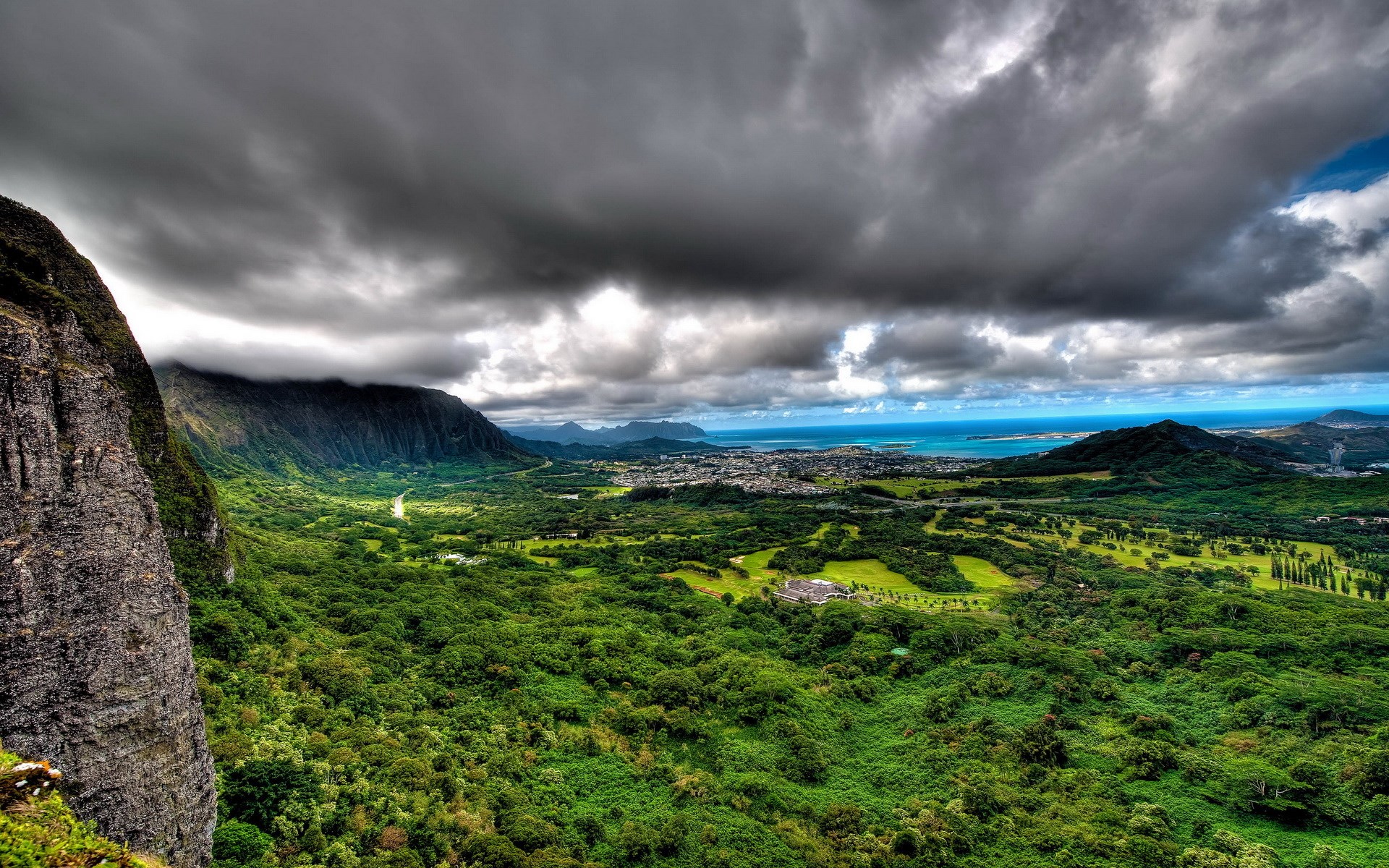 Dramatic mountain valley overlooking a coastal town HD Wallpaper