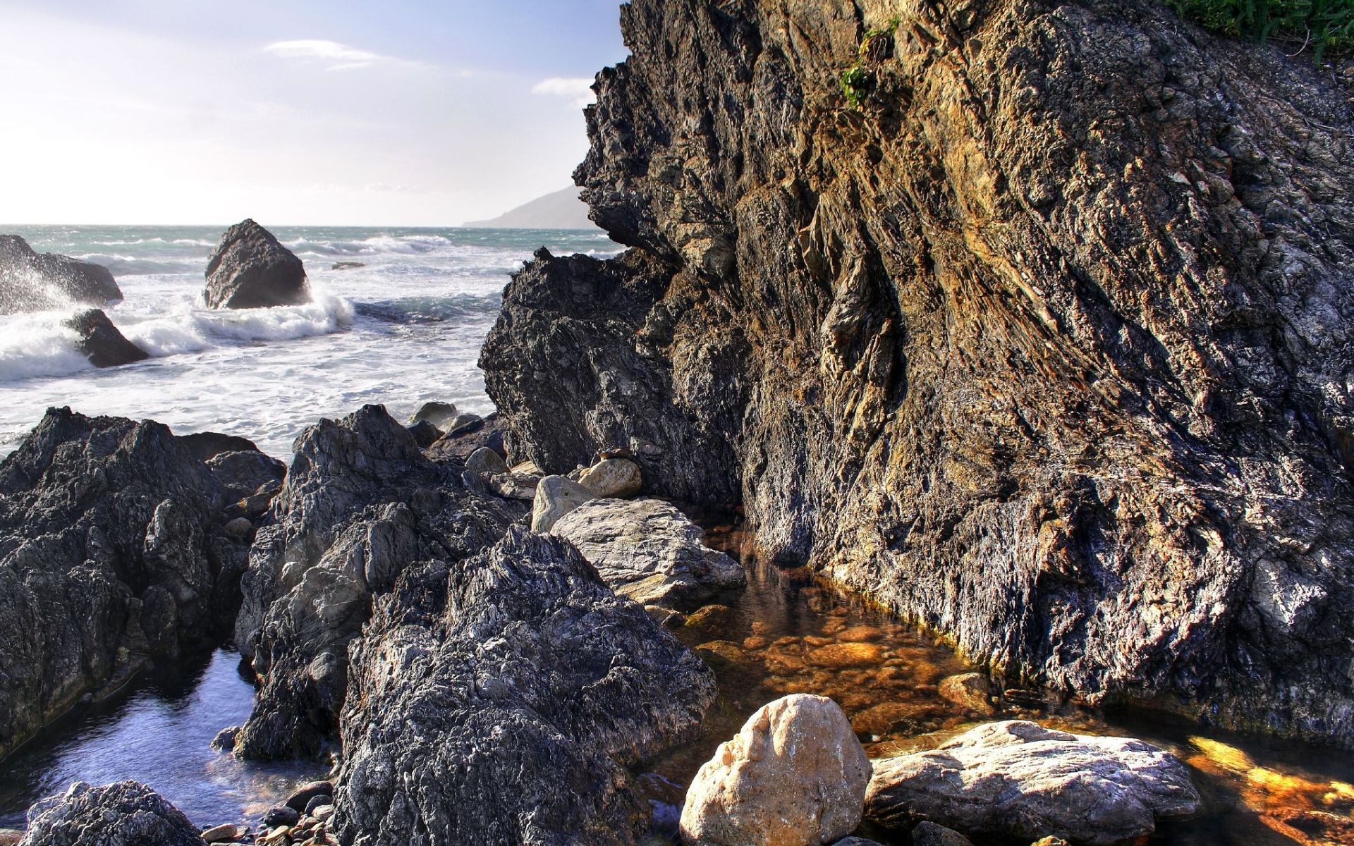 Rocky coastline with waves crashing against rocks HD Wallpaper