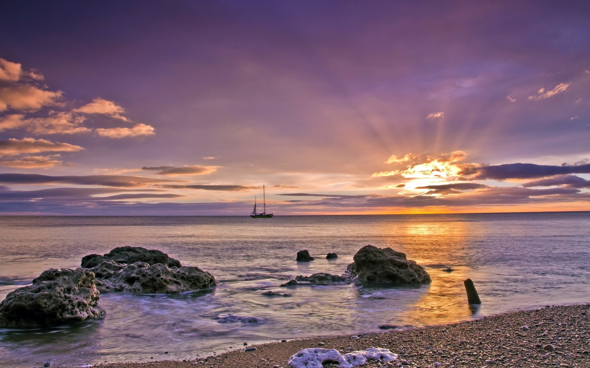Sailboat on the ocean at sunset with rocky shore HD Wallpaper
