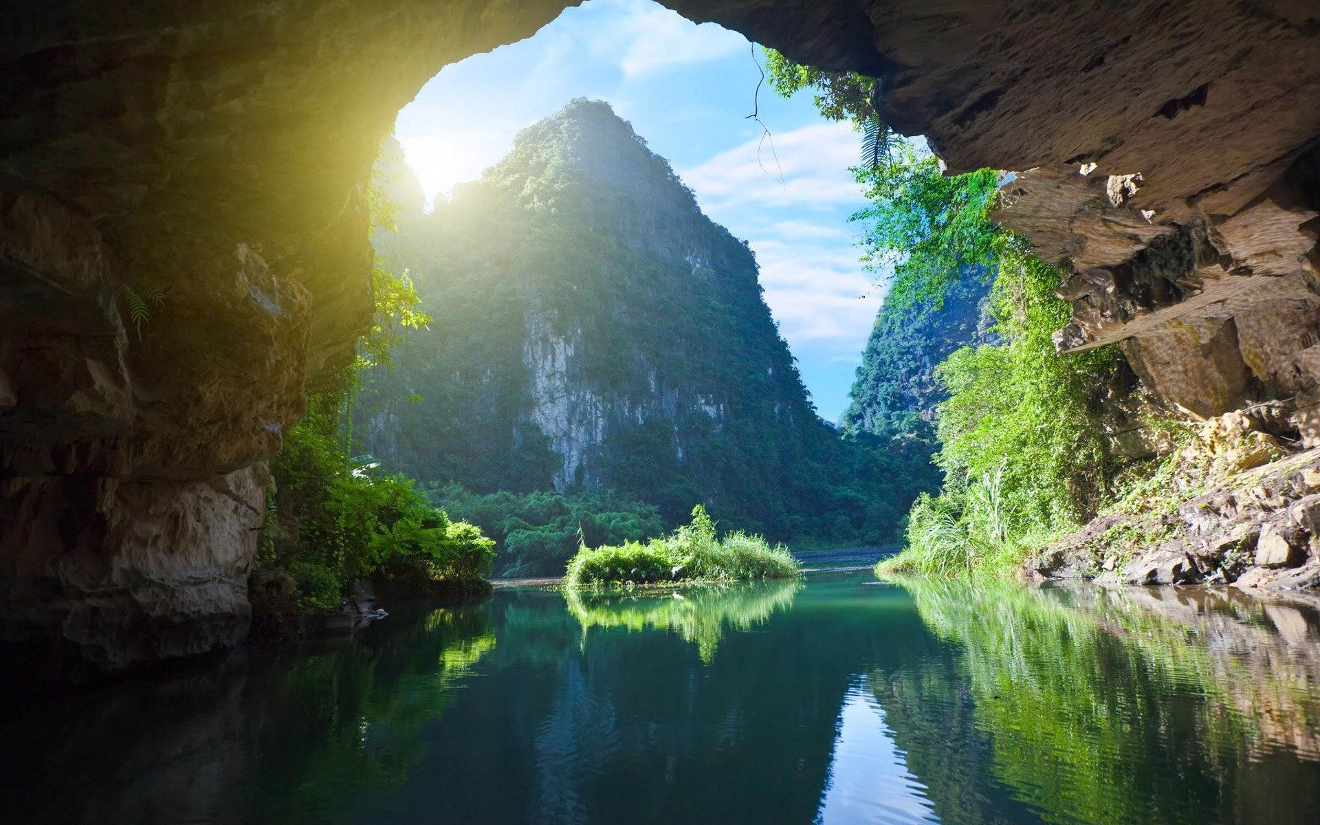 Cave entrance overlooking a river and karst mountains HD Wallpaper