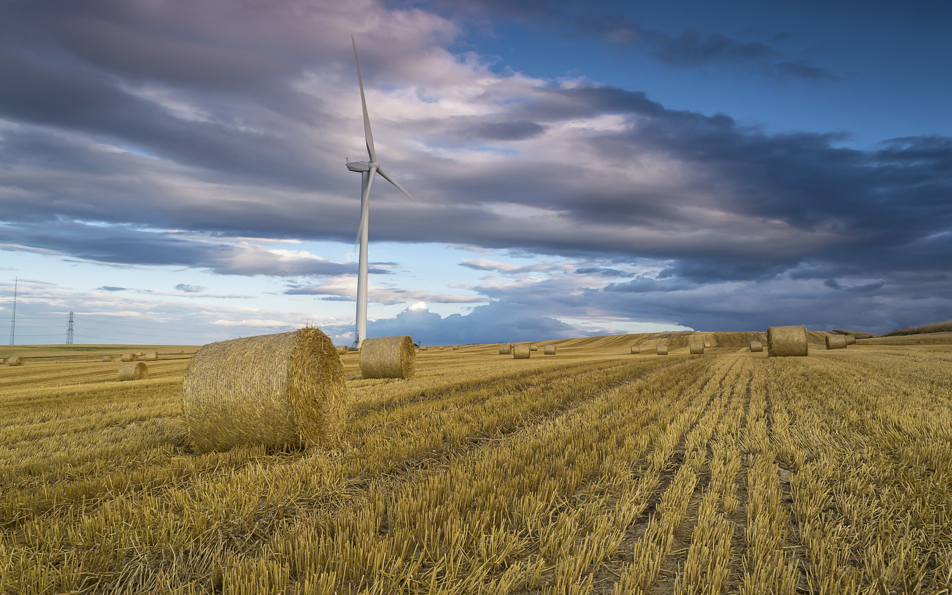 Wind turbine in a field of hay bales HD Wallpaper