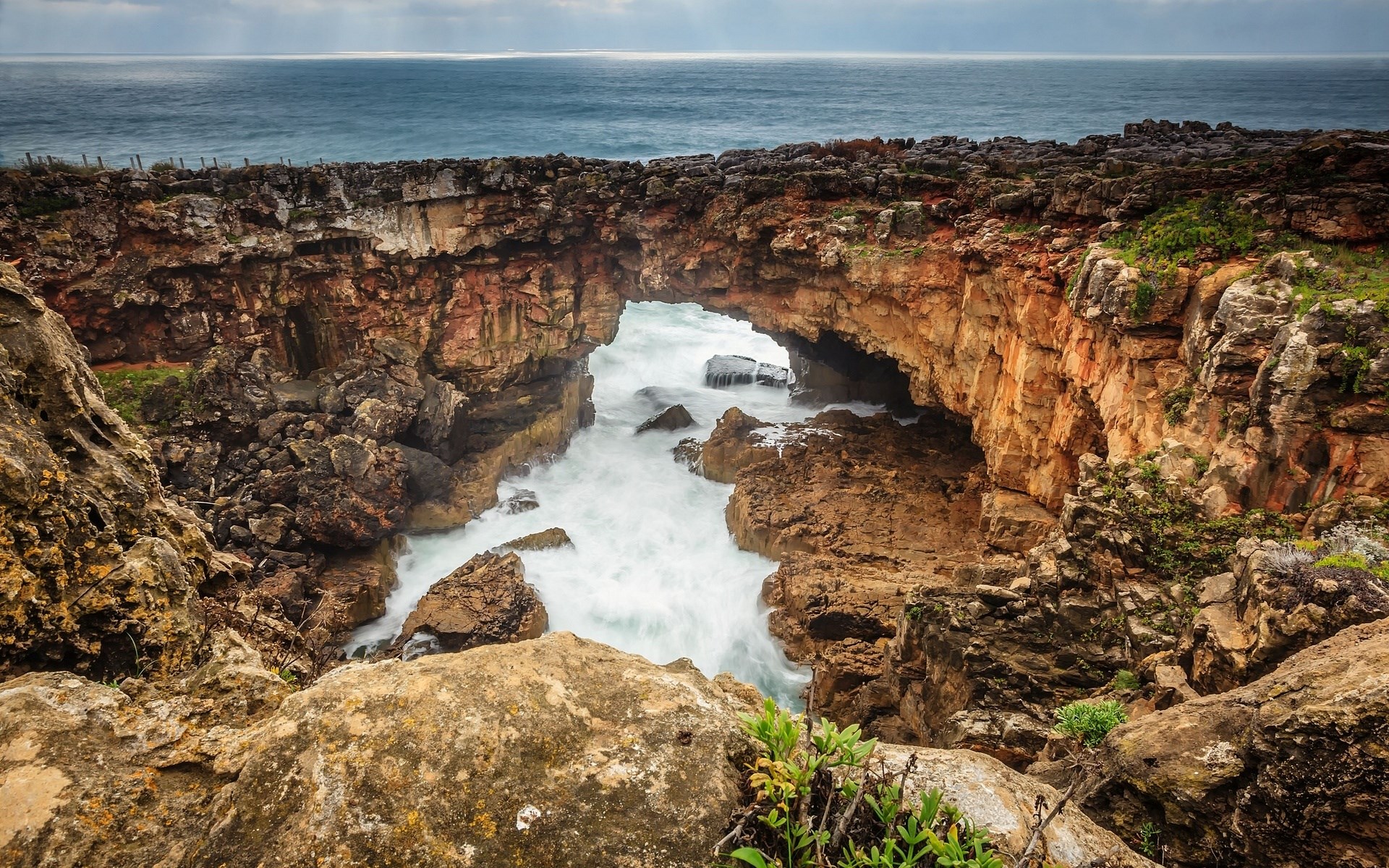 Ocean waves crashing through a rock arch HD Wallpaper