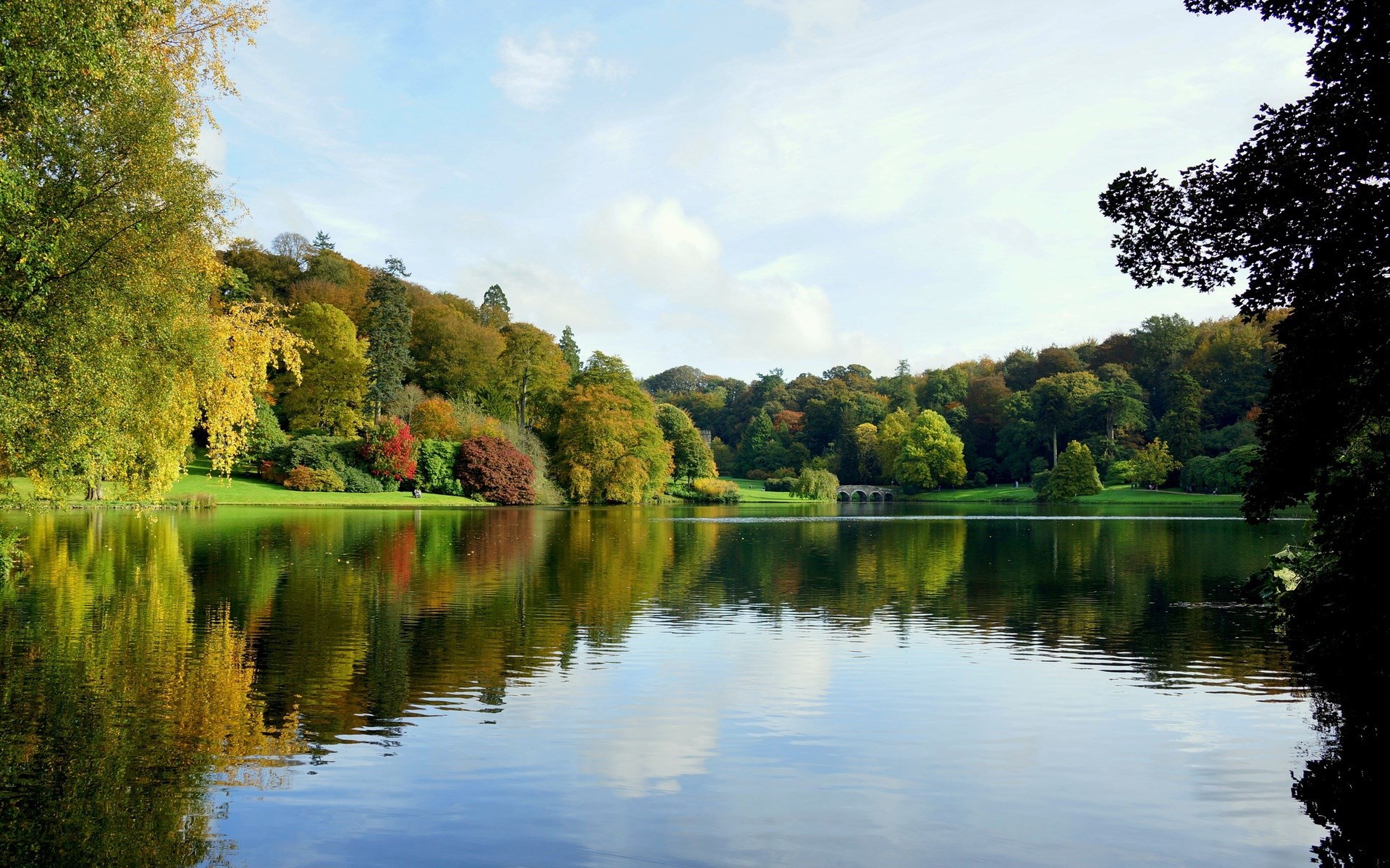 Autumn trees reflected in a lake with a bridge HD Wallpaper