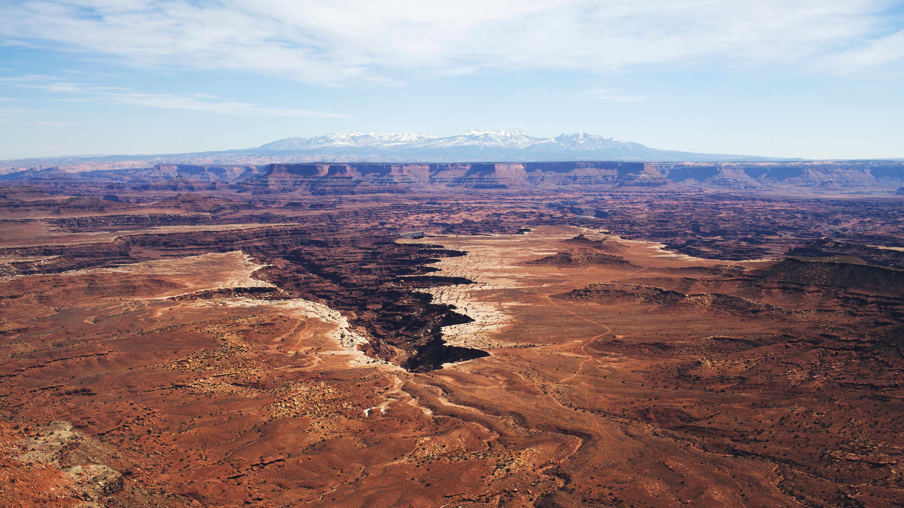 Canyonlands National Park with snow-capped mountains in distance HD Wallpaper