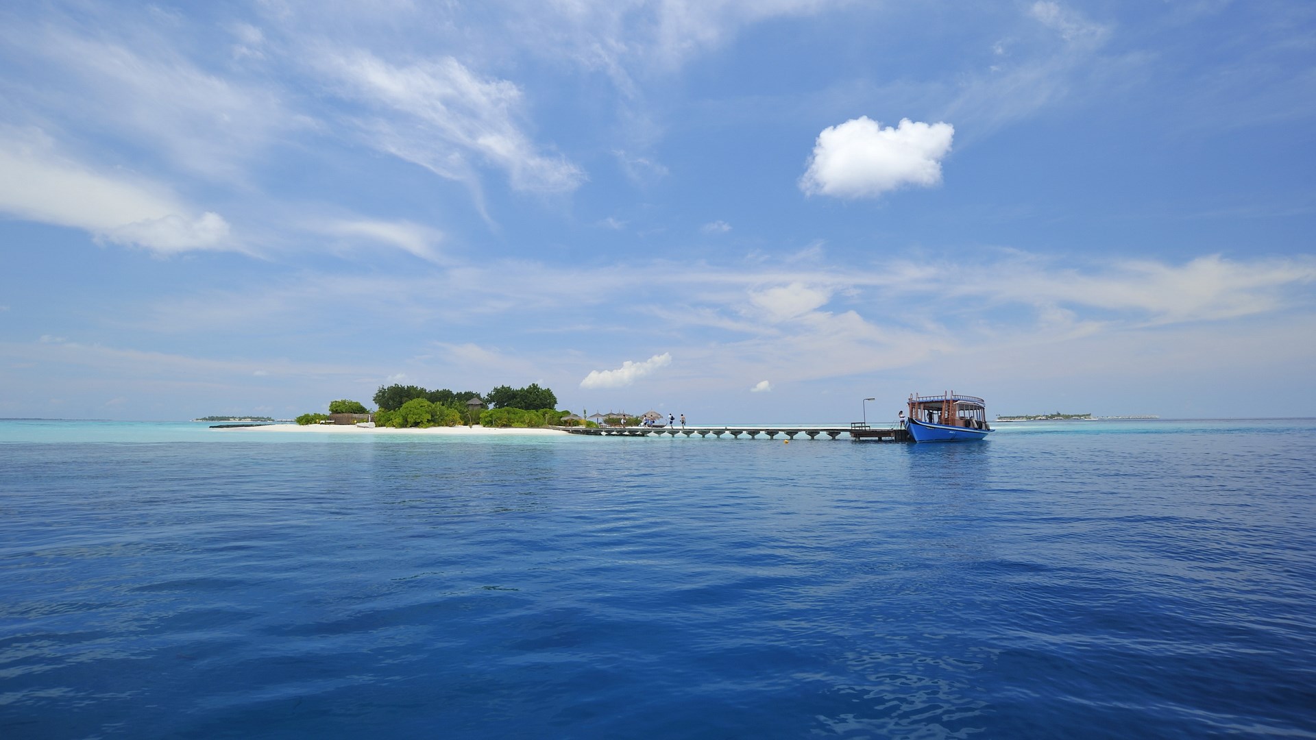 Island with a pier and a boat in the ocean HD Wallpaper