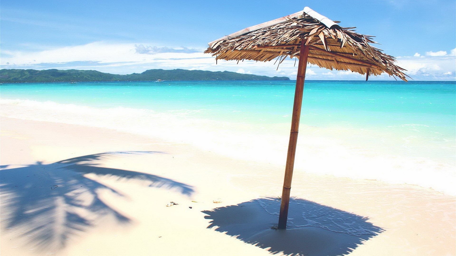 Thatched umbrella on a tropical beach with turquoise water HD Wallpaper