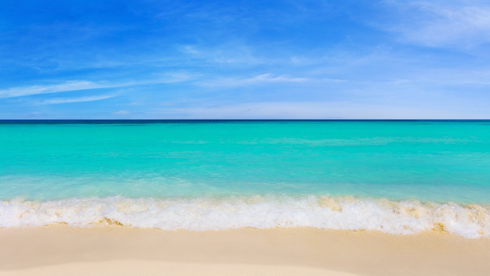 Turquoise ocean waves on a sandy beach under a blue sky HD Wallpaper