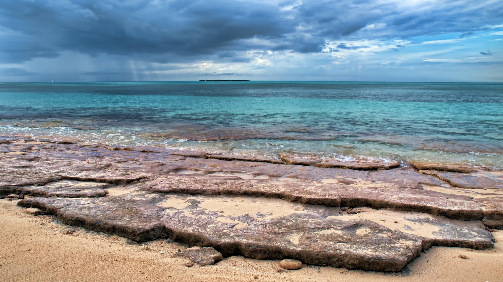 Rocky beach with turquoise water and stormy clouds HD Wallpaper