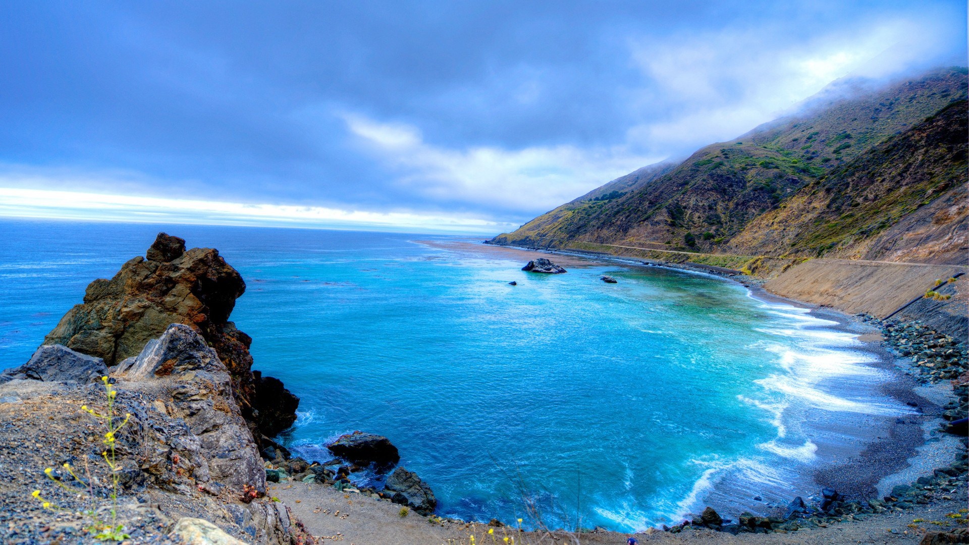 Coastal highway overlooking a turquoise bay with rocky cliffs HD Wallpaper