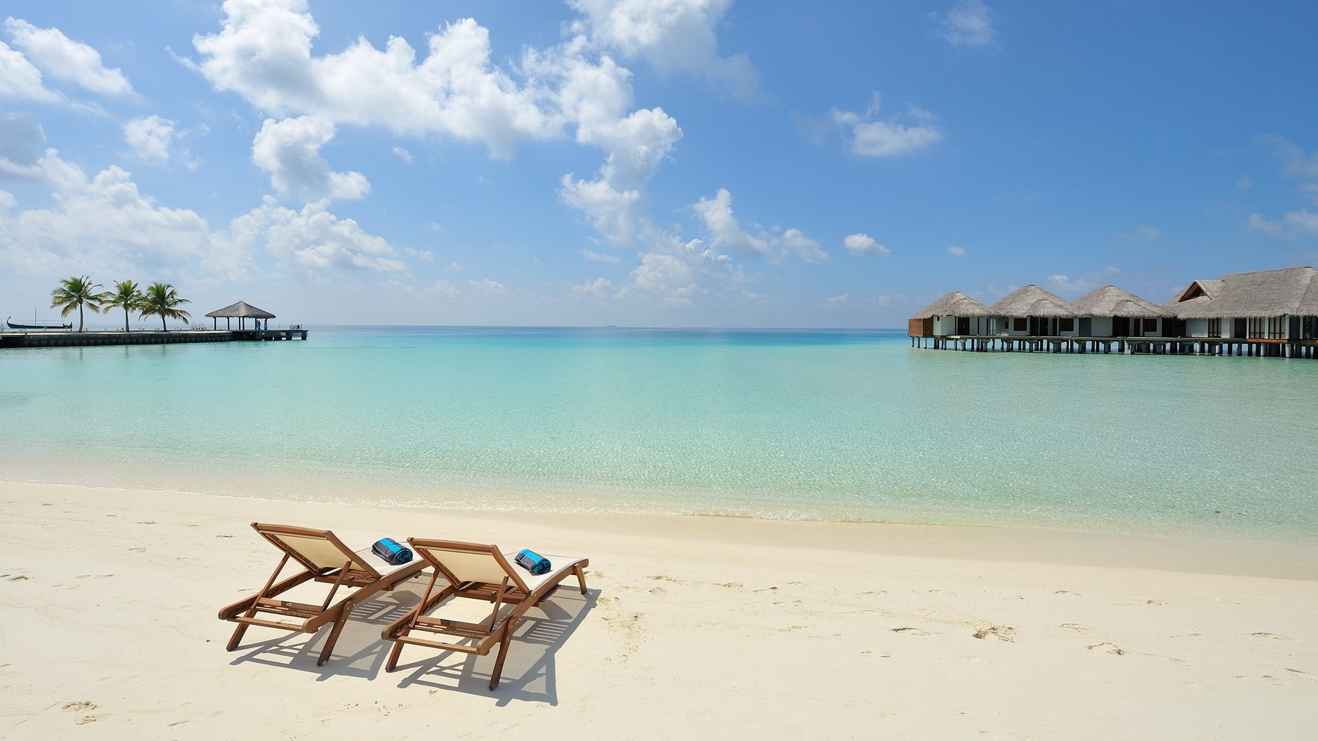 Beach with lounge chairs and overwater bungalows HD Wallpaper