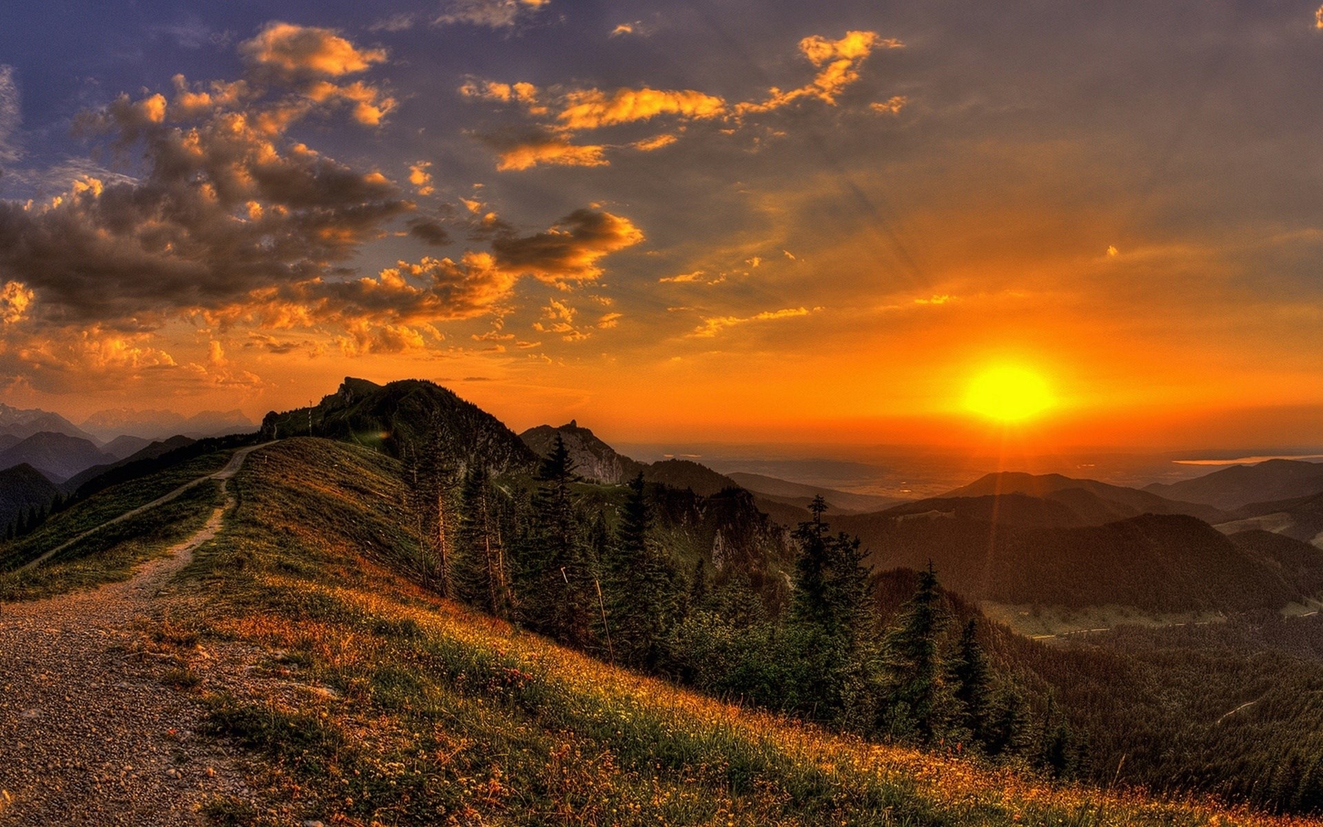 Sunset over mountain range with a hiking path HD Wallpaper