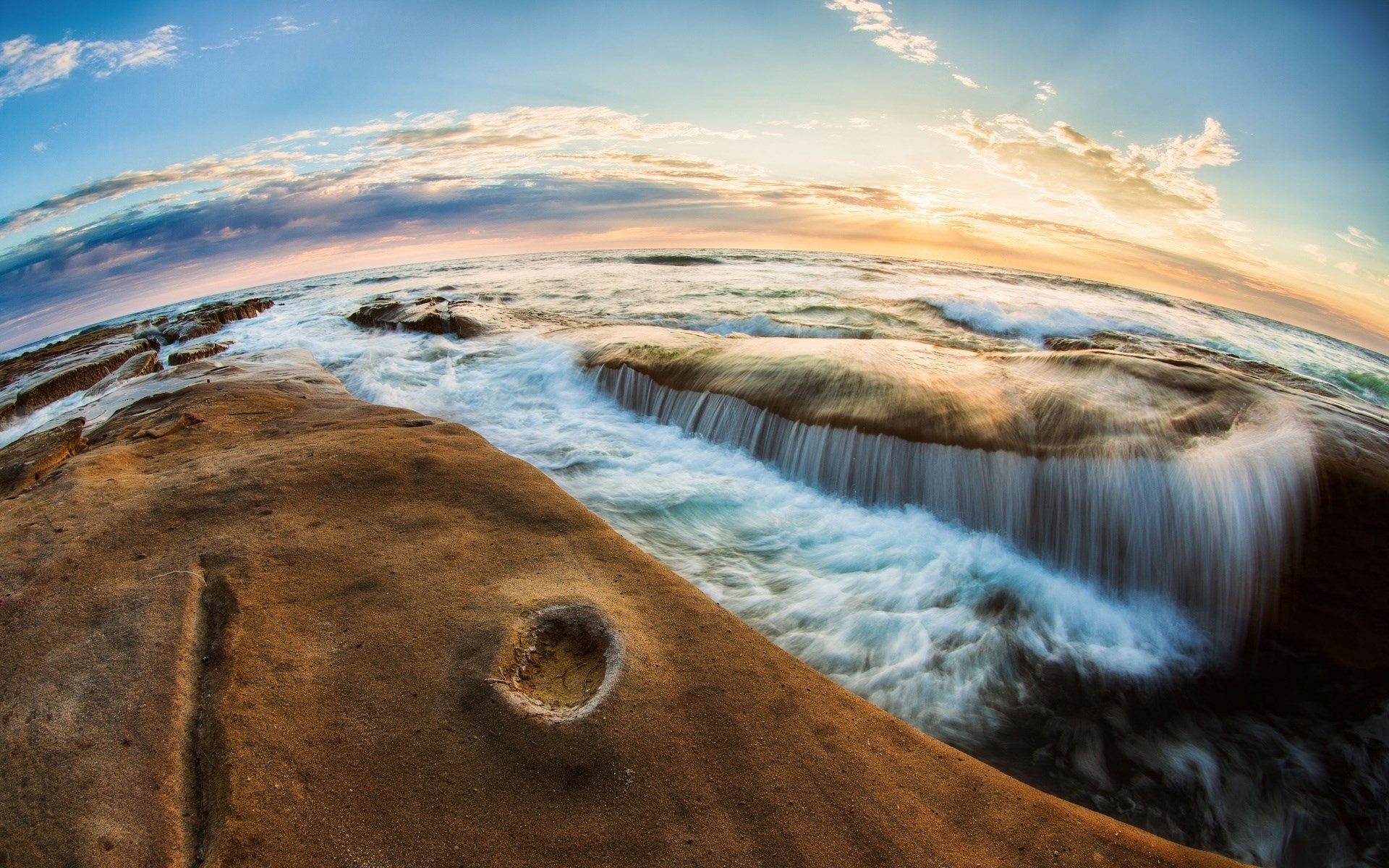 Ocean waves crashing over rocks at sunset HD Wallpaper