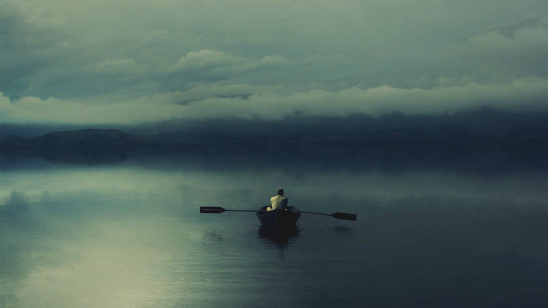 Man rowing a boat on a misty lake HD Wallpaper