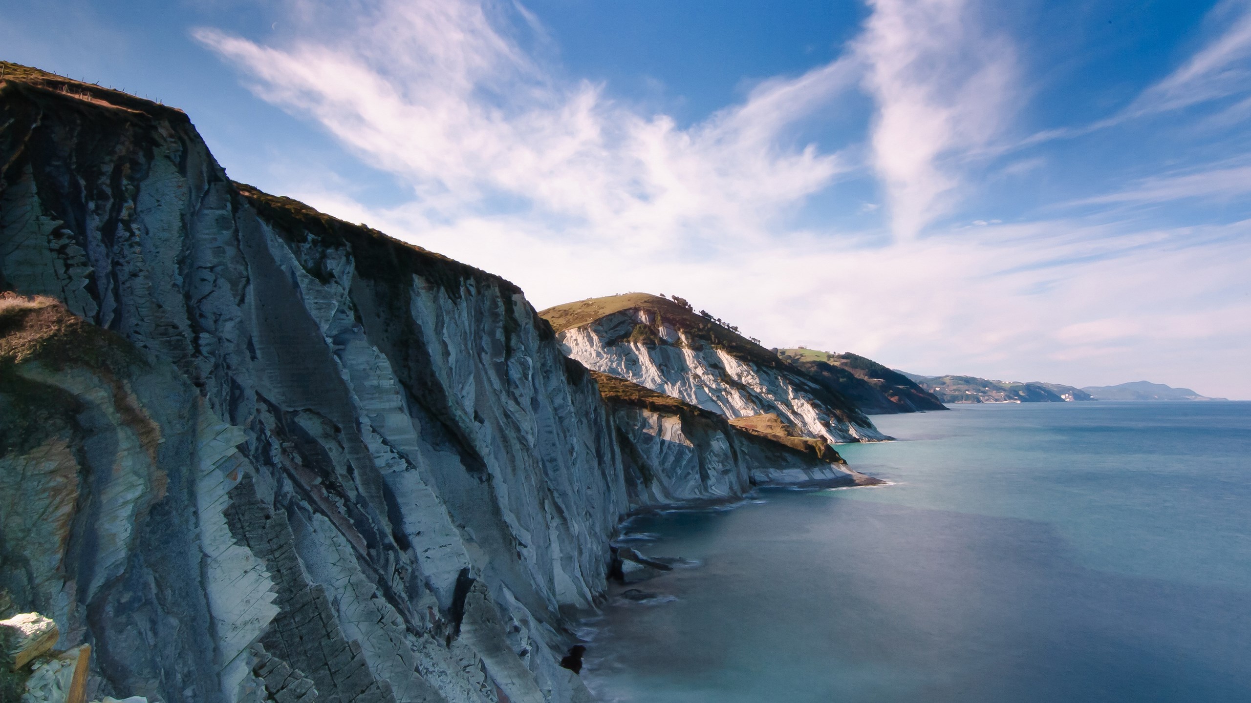 Cliffs overlooking the ocean under a cloudy sky HD Wallpaper