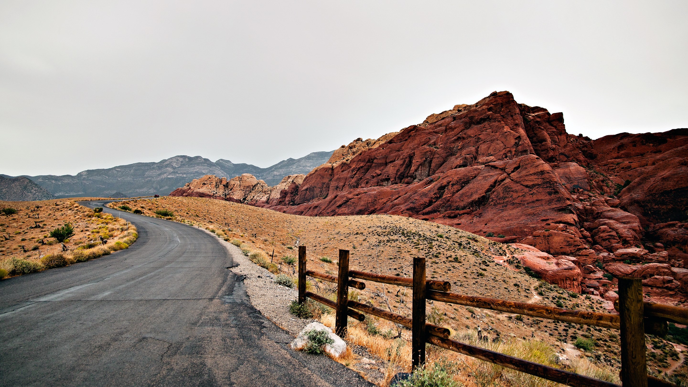 Desert road with red rock mountains and wooden fence HD Wallpaper