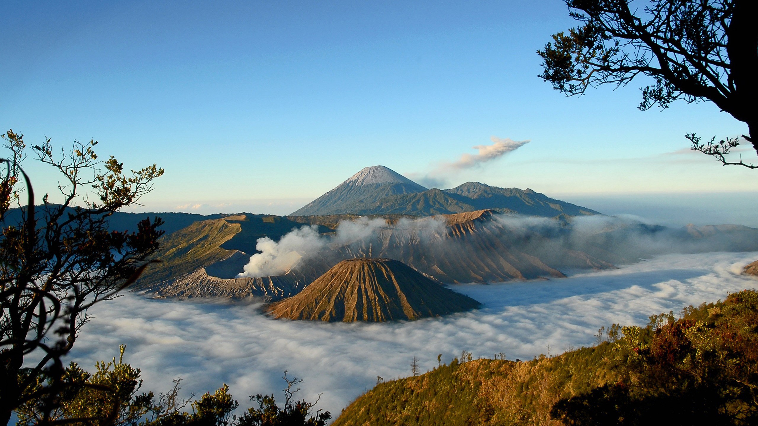 Volcanoes shrouded in mist under a clear blue sky HD Wallpaper