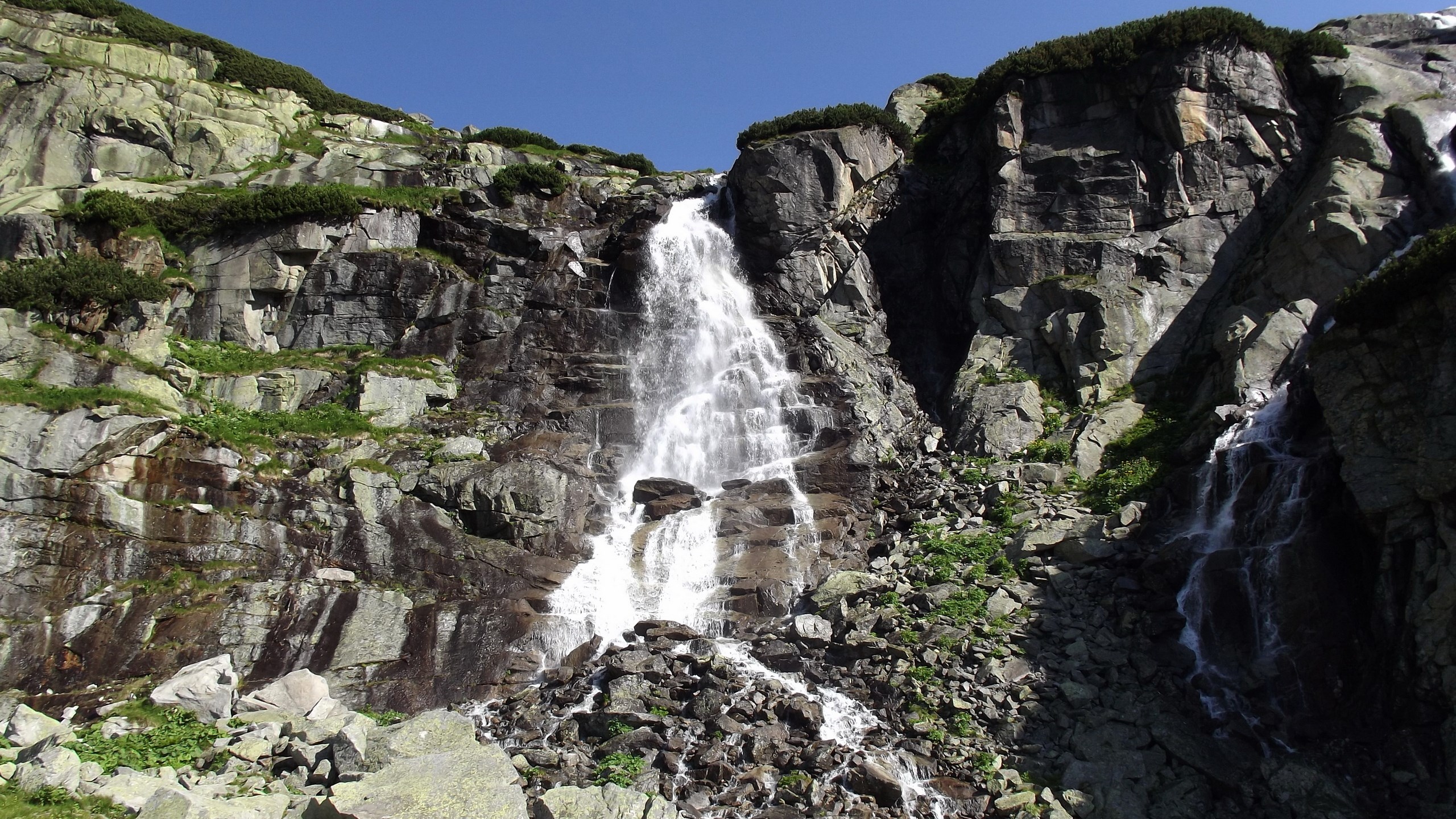 Waterfall cascading down a rocky mountain slope HD Wallpaper
