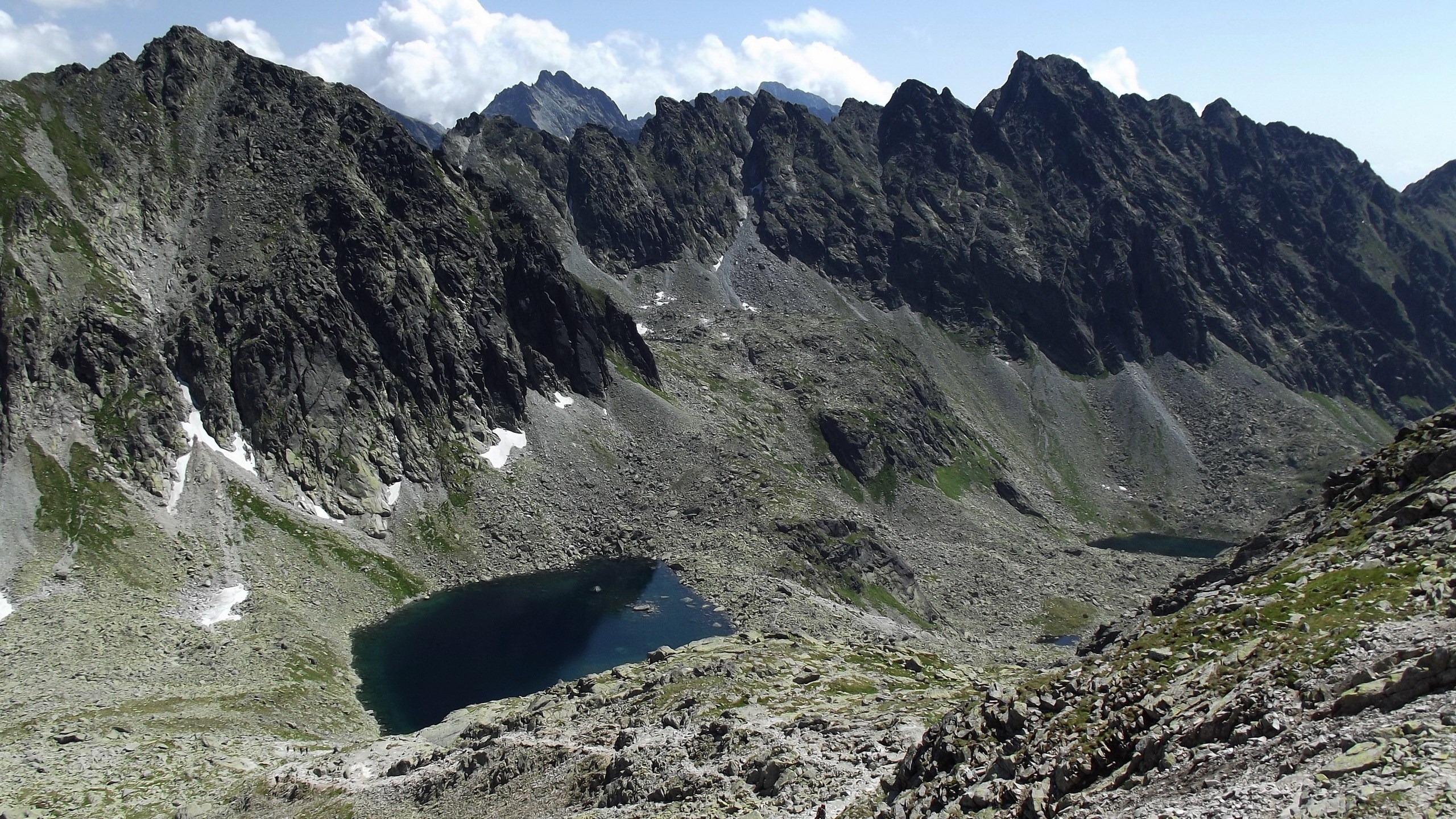 Mountain range with a dark lake and rocky slopes HD Wallpaper