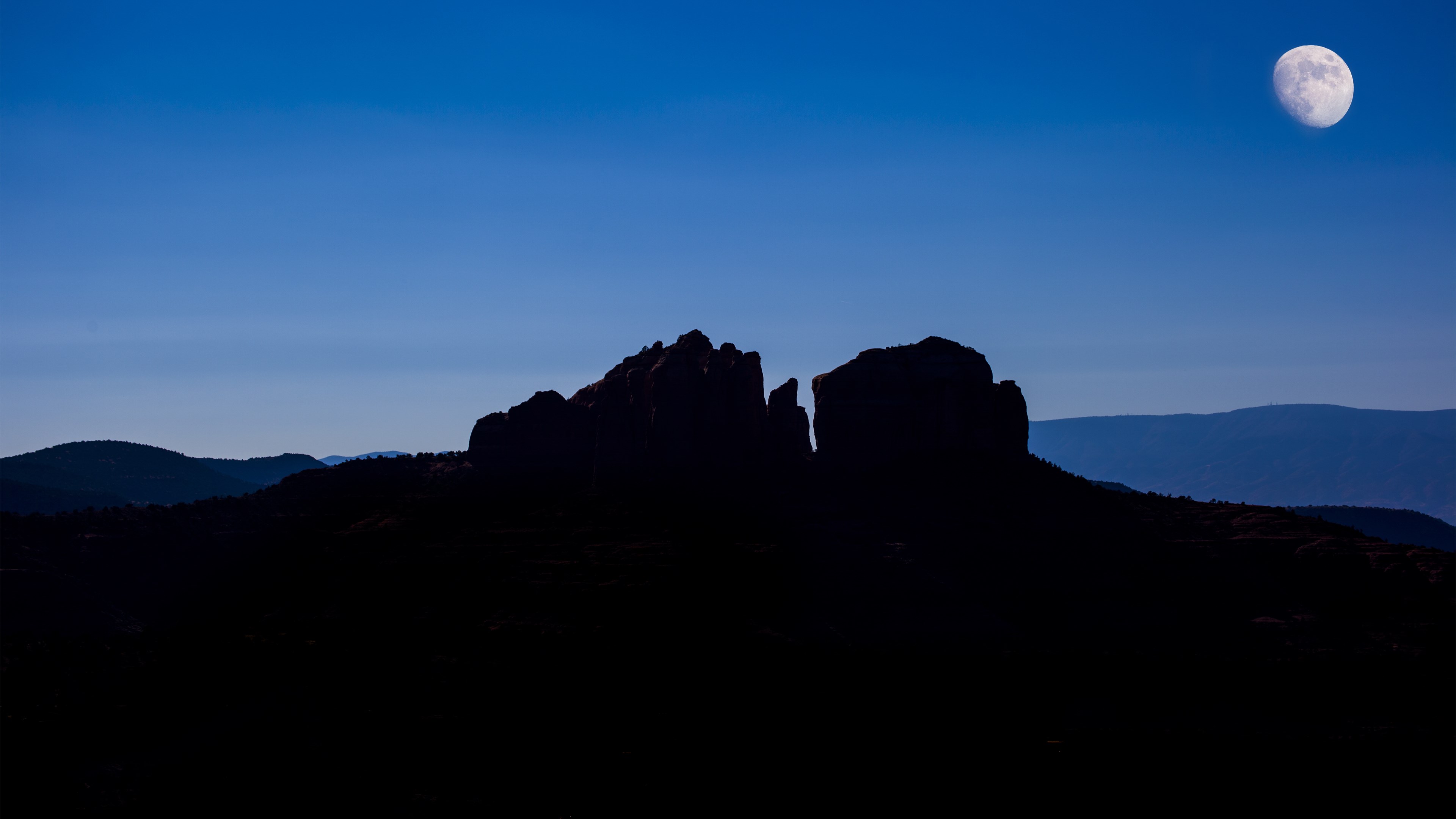 Moon over silhouetted rock formations and mountains HD Wallpaper