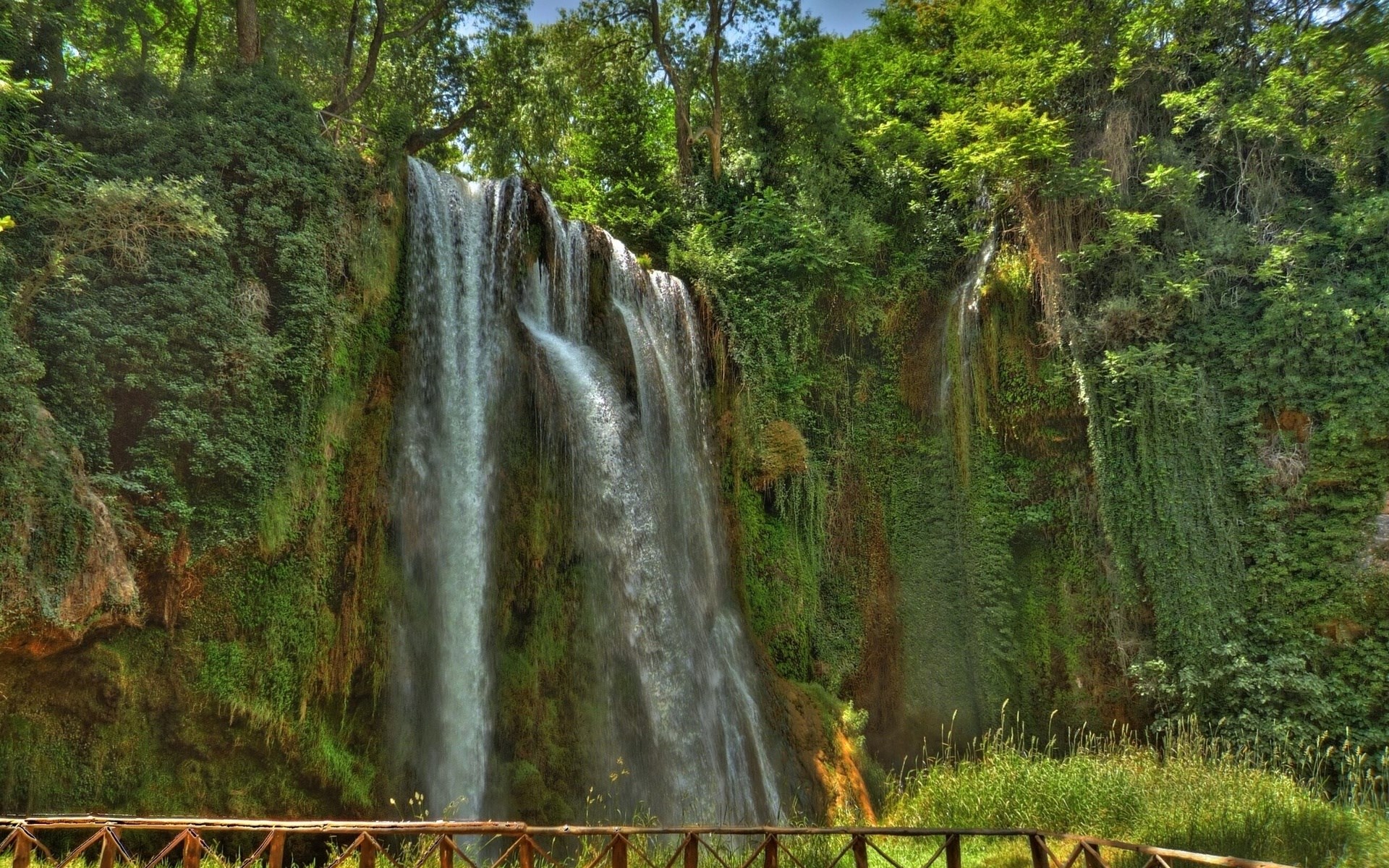 Waterfall cascading down a moss-covered cliff face HD Wallpaper