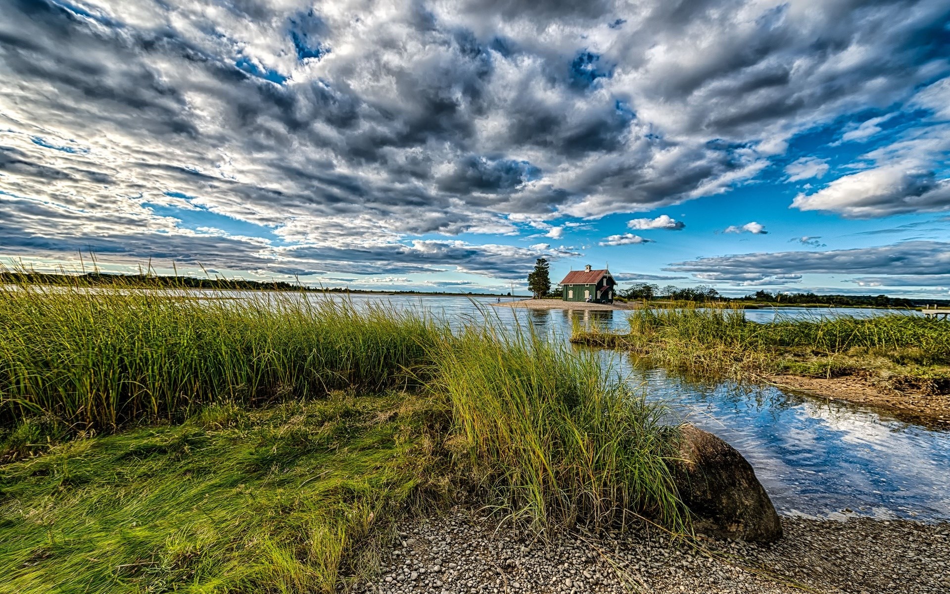 A small house on an island in a lake under a cloudy sky HD Wallpaper