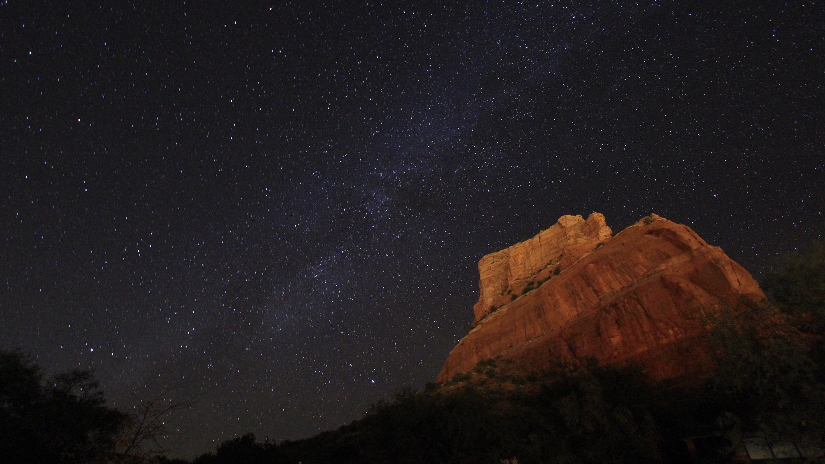 Red rock formation under a starry night sky HD Wallpaper